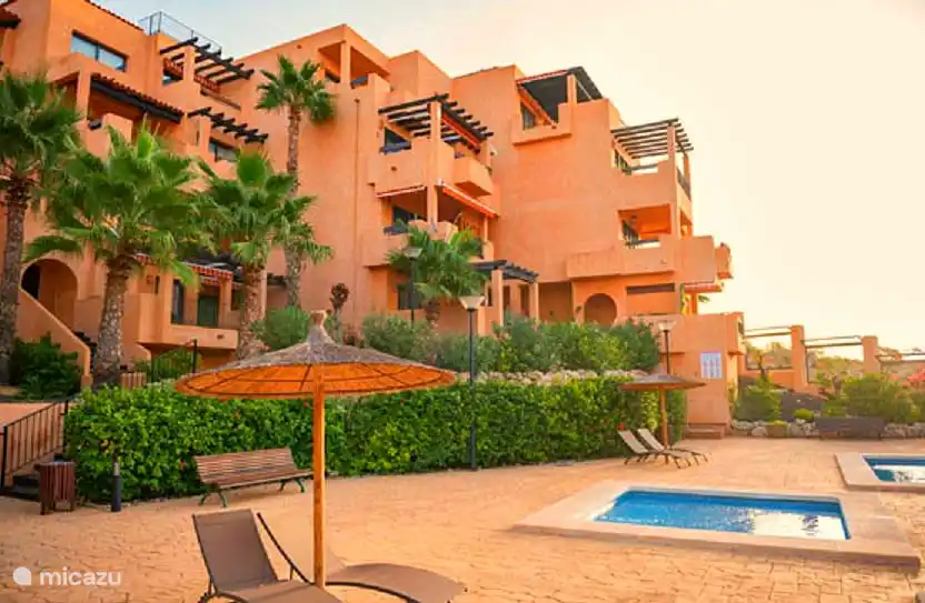 Les belles chaises longues au bord de la piscine avec parasols en chaume.