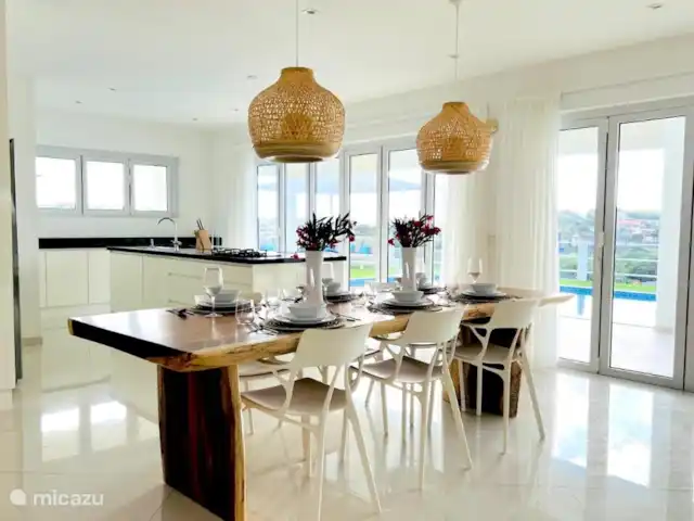 Villa Leoni en Curazao, Banda Arriba (este), Brakkeput Abou - apartamento Permanecerá conectado en el gran salón con cocina abierta y puertas correderas a la piscina. Tome asiento en la mesa con tronco de árbol de madera tropical de Wood66 en una silla de diseño italiano Kartell AI.