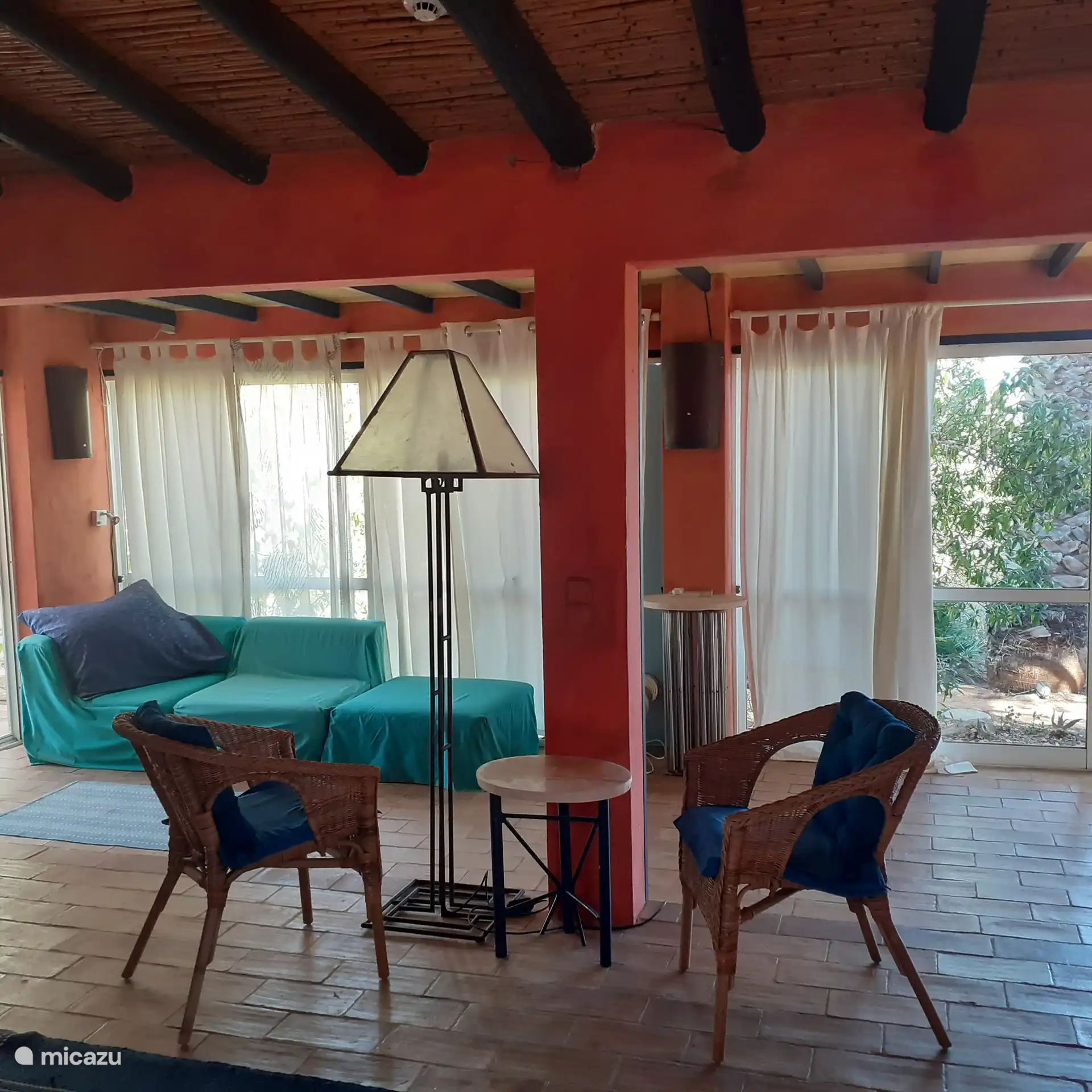 Ein Blick in den Lebensraum auf die breite Fensterfront einer Sitzecke und dem schoenen gruenen Sofa.