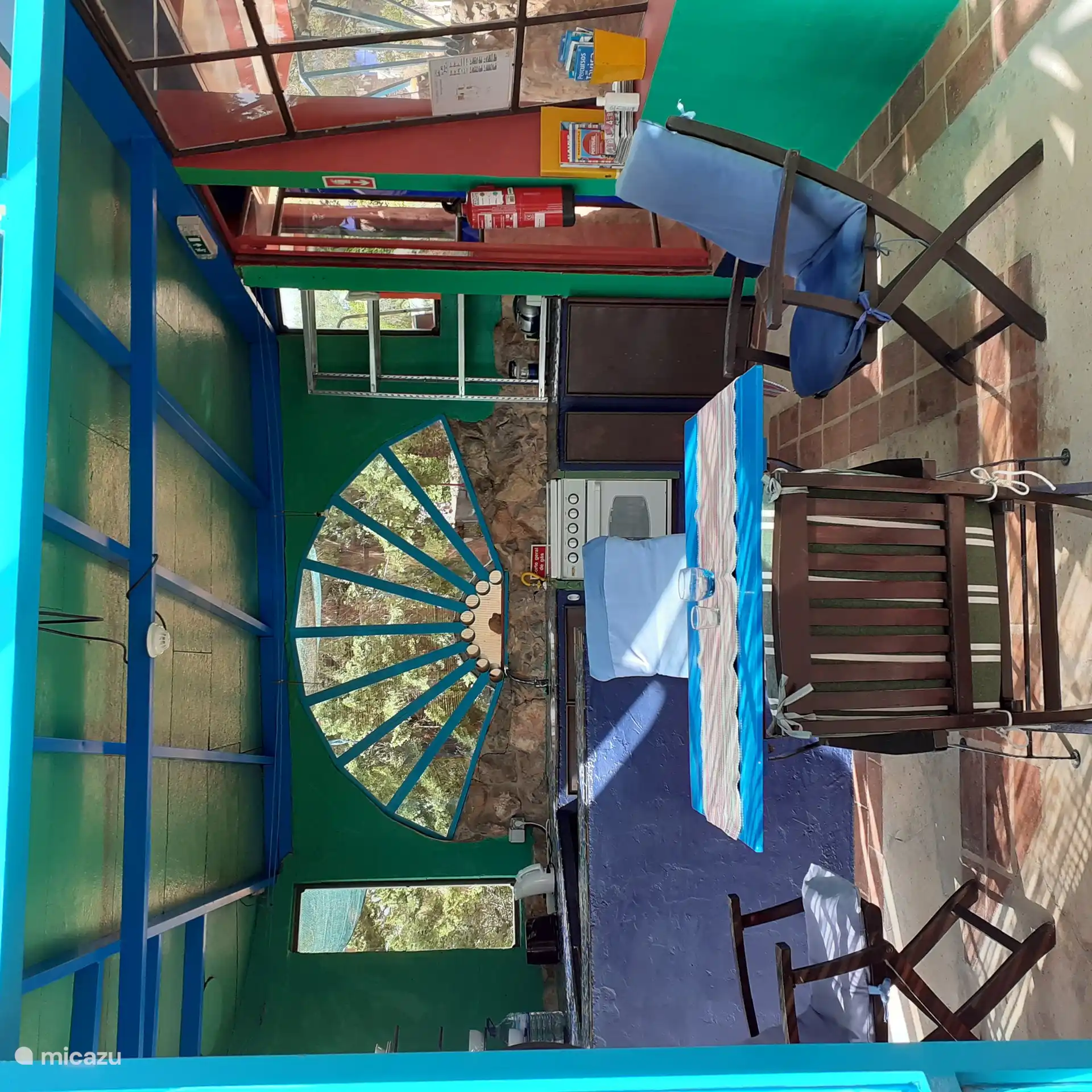 Schoener Einblick in die tuerkis-blaue Kueche nebst Essplatz und Stuehlen,