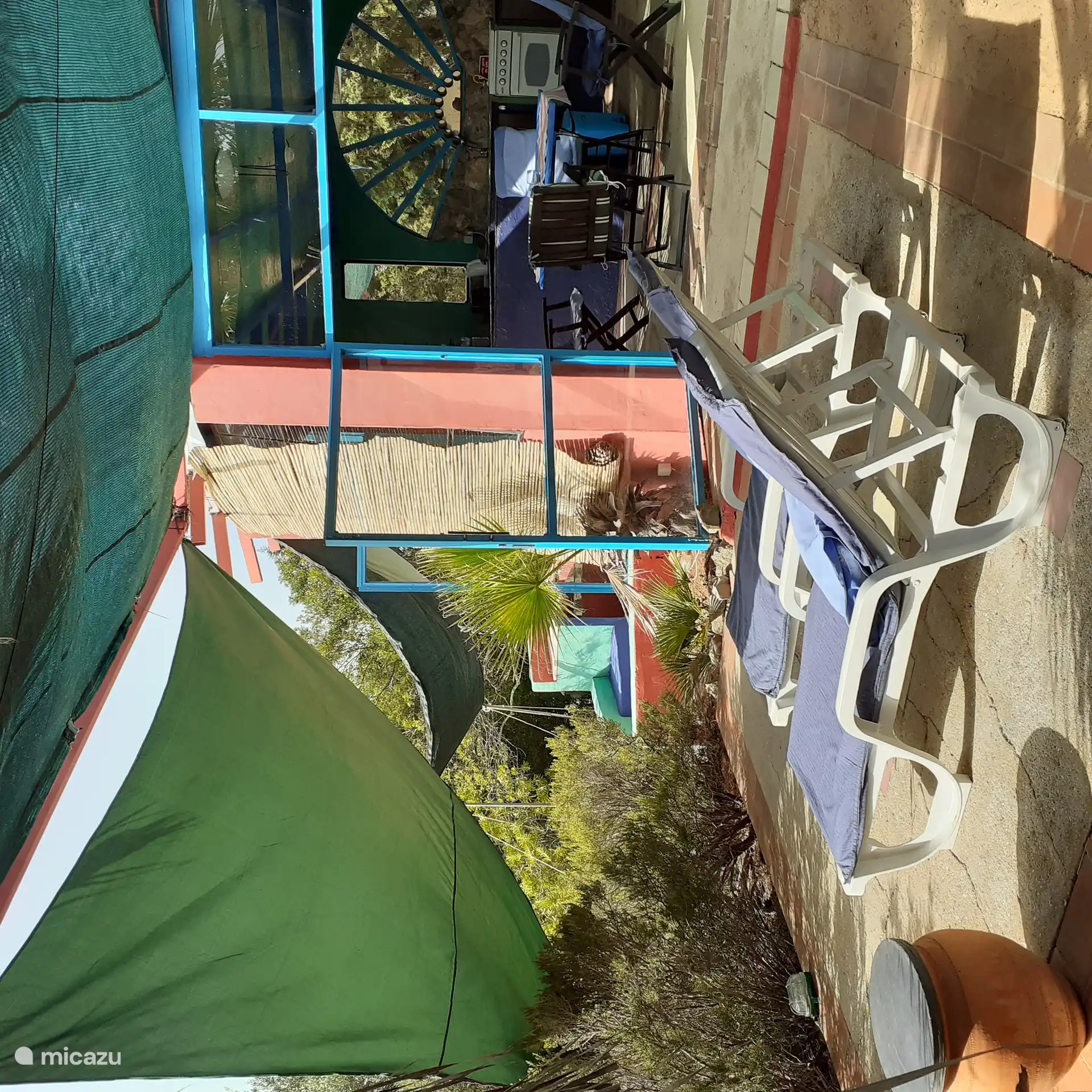 Die abgeschattete Terrasse mit Sonnenliegen die gleich an das Kuechenhaus mit seinen weiten Tueren angrenzt 