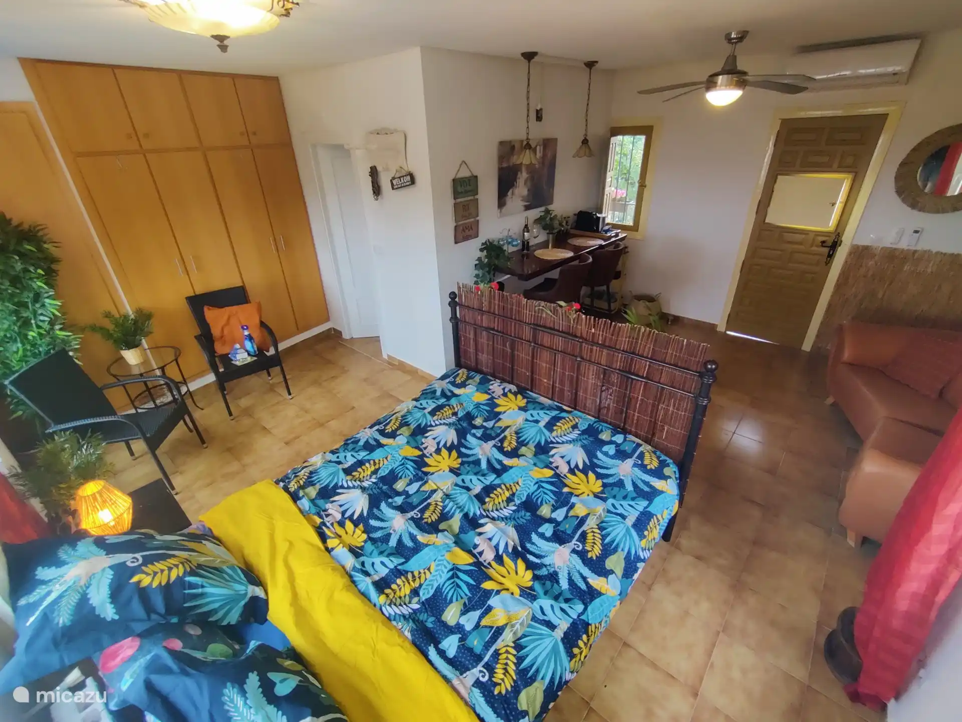 Descripción general de la habitación con cama, zona de estar, sofá y bar con todas las instalaciones (café, hervidor, frigorífico, microondas/horno, aire acondicionado)