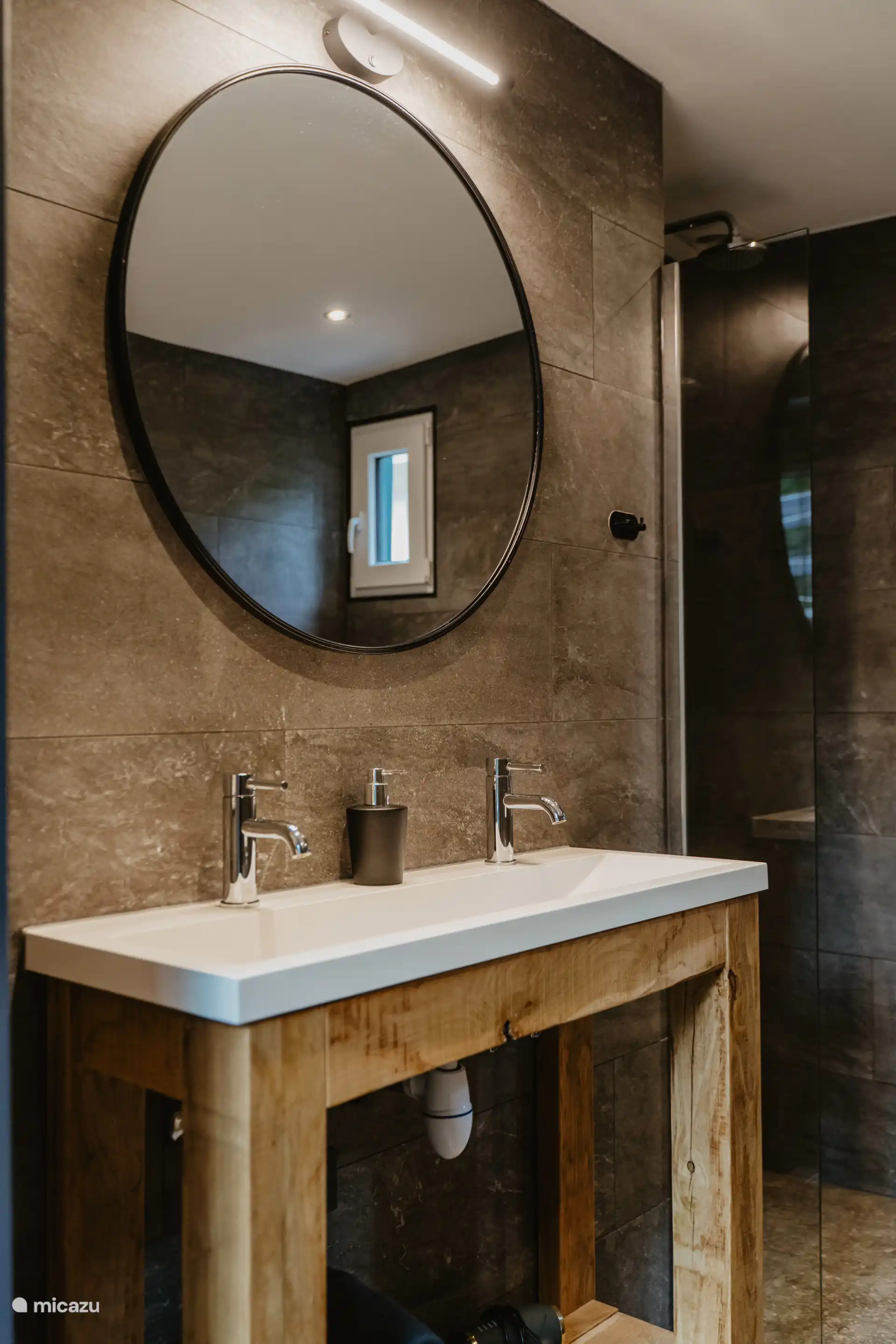 Double lavabo avec un grand miroir avec de l’éclairage au-dessus.