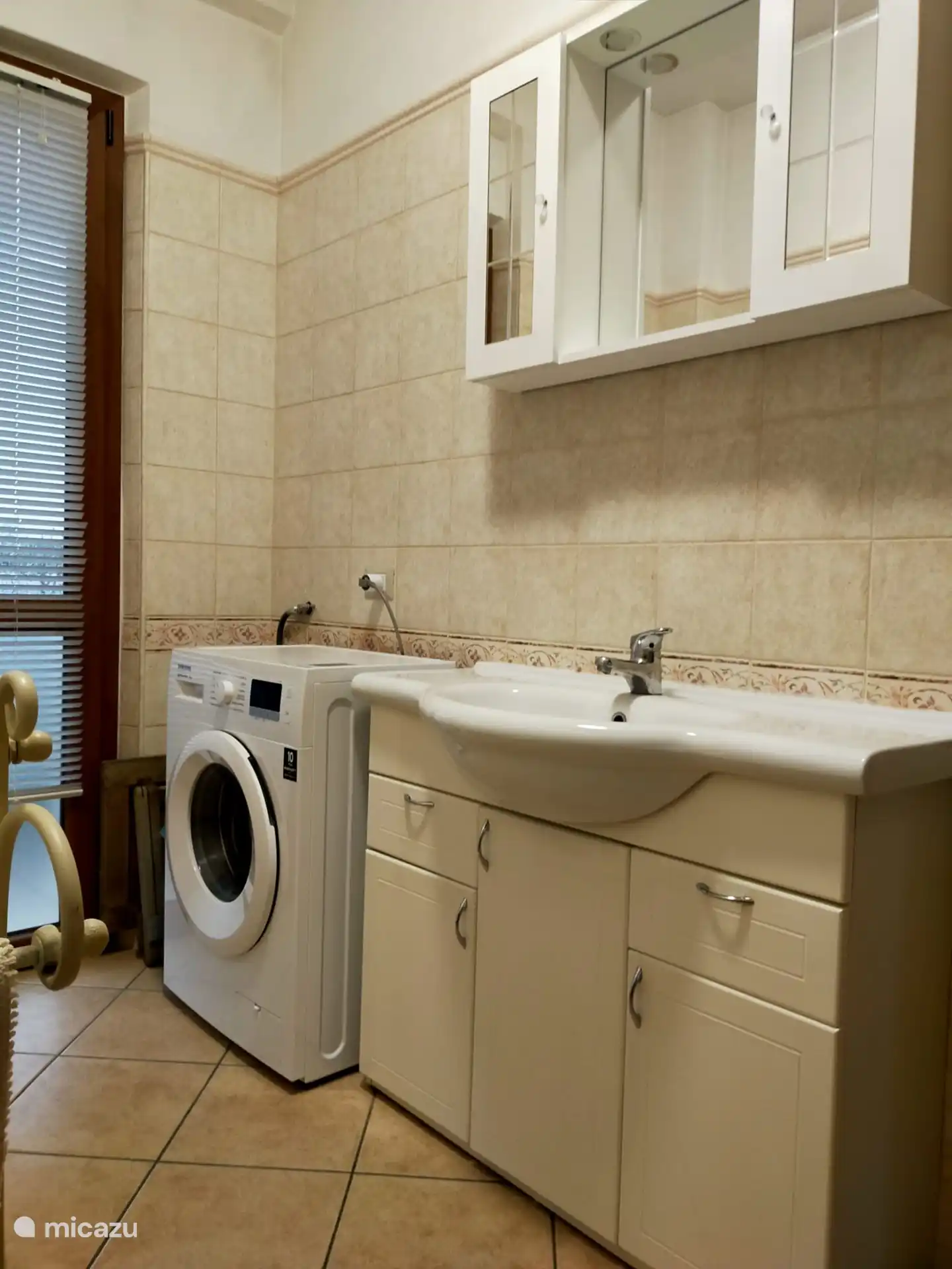 The bathroom with sink and washing machine.