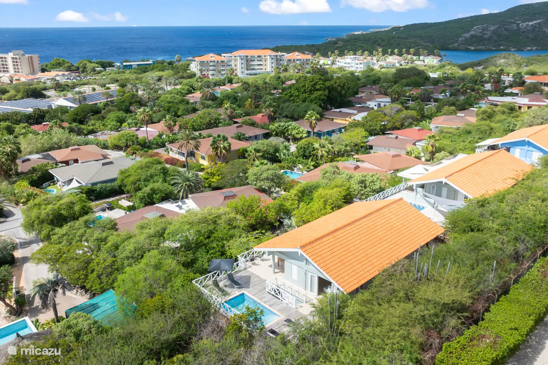 The house is located on a hilly plot of 200 m2 and is surrounded by plants. 