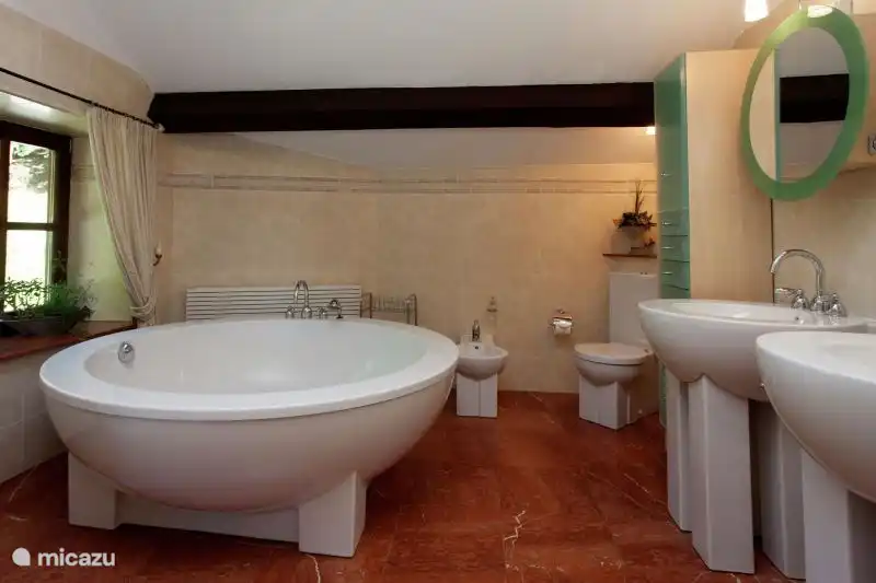 Badezimmer mit runder Badewanne, Dampfkabine/Dusche, Toilette, Bidet und Doppelwaschbecken