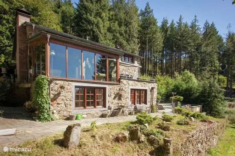 Auf der Rückseite des Hauses, hinter der Glasfassade, befindet sich der Wintergarten mit gemütlicher Sitzecke und Blick in den parkähnlichen Garten