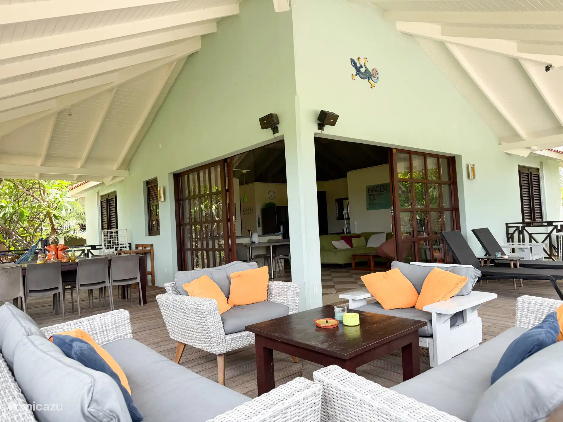 Preciosa terraza cubierta grande con salón, mesa de comedor, tumbonas, hamacas y barbacoa de gas