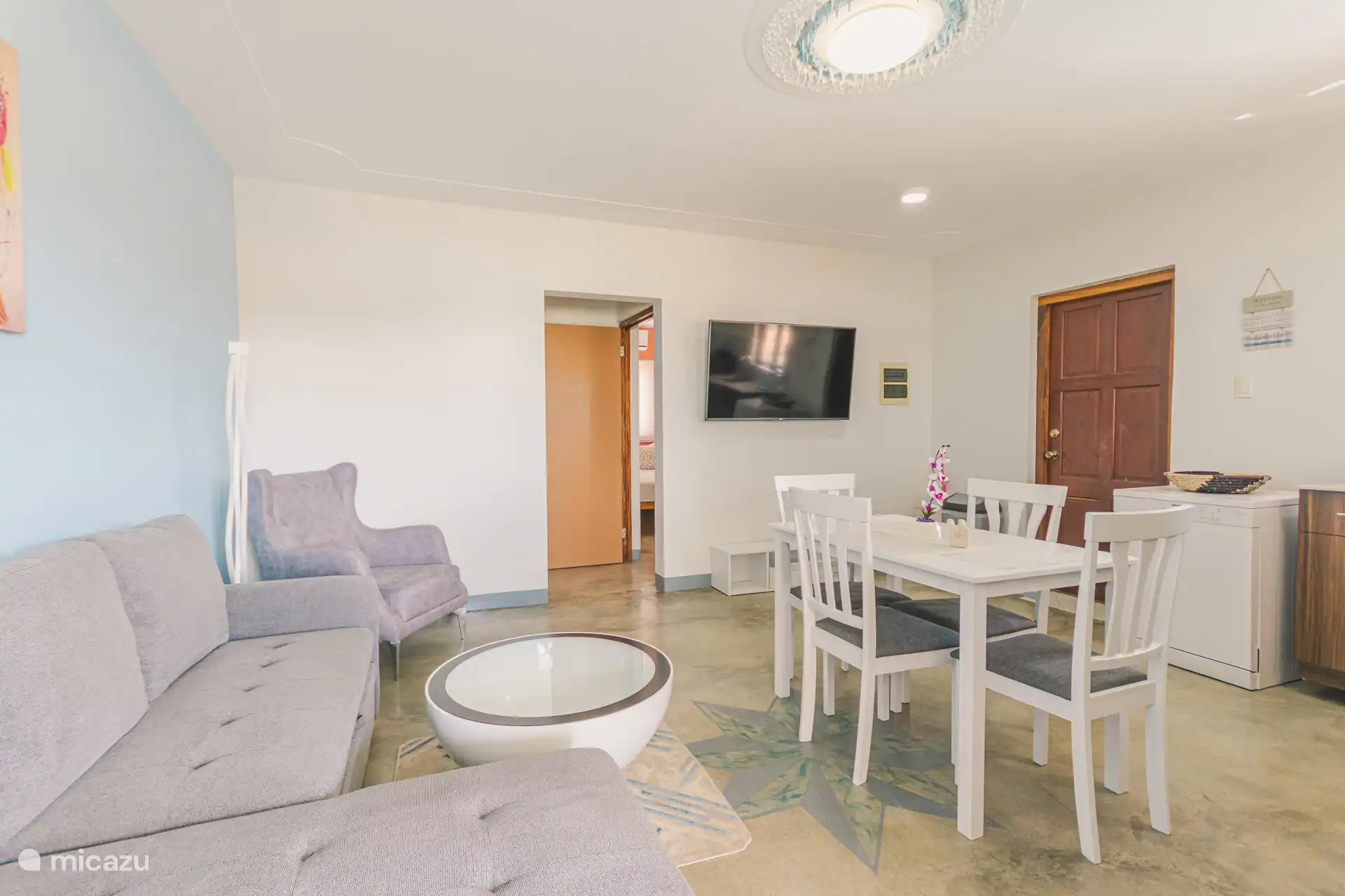 Living room with kitchen, dining table, sitting area and TV with many international channels