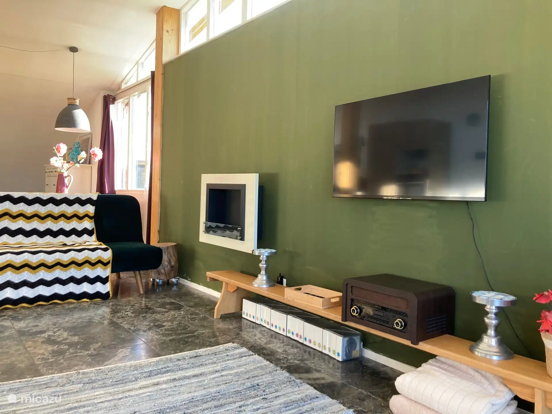 Im Wohnzimmer: ein Smart-TV, ein CD-/LP-/Radio-Player, CDs, LPs und ein dekorativer Kamin