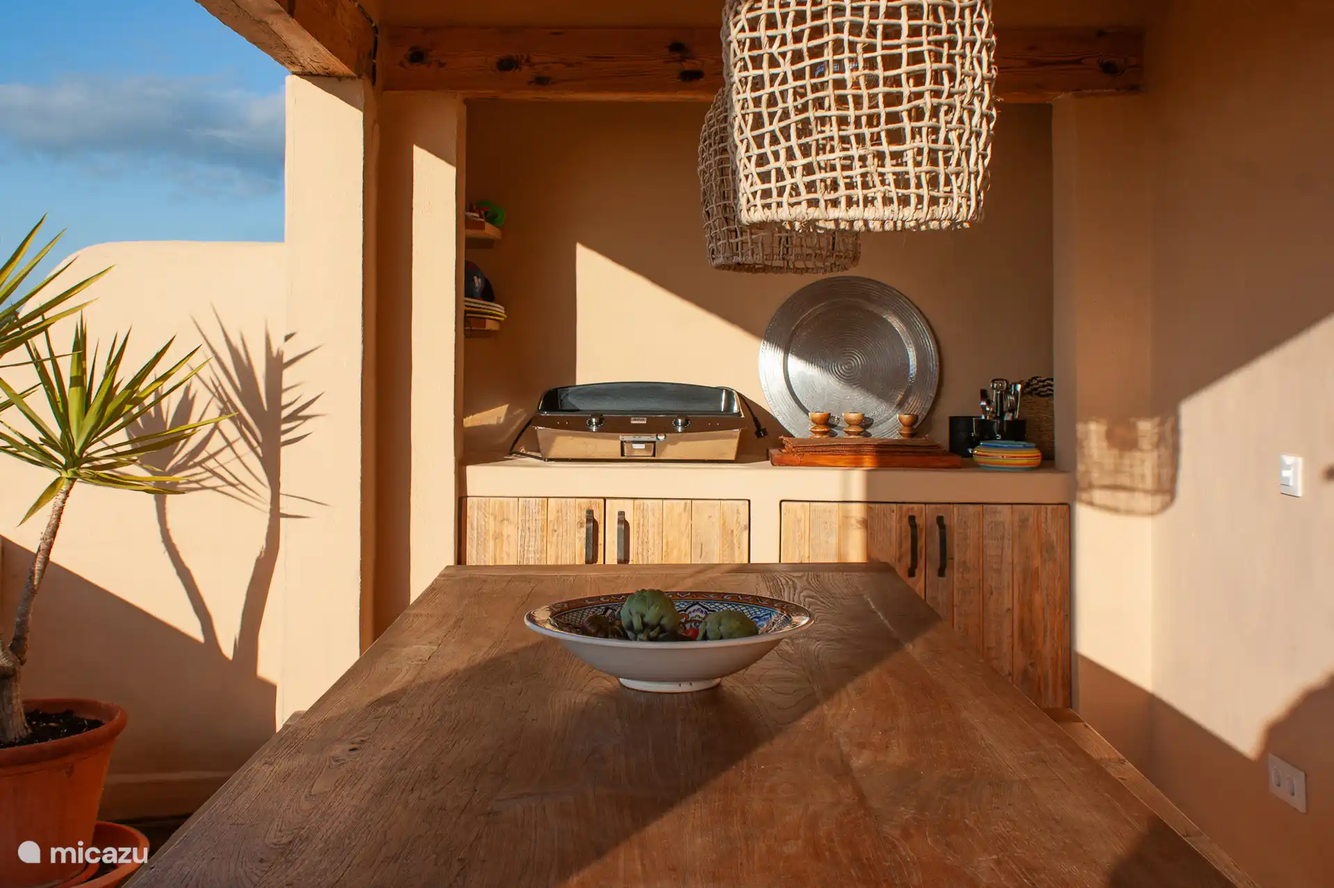 Overdekt terras op de begane grond met een ruime eettafel voor 6 personen en een buitenkeuken.