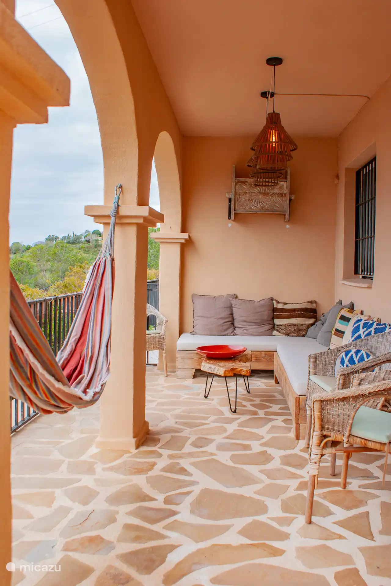 Tweede terras op de benedenverdieping met een zithoek, hangmat en twee zonnebedden.
