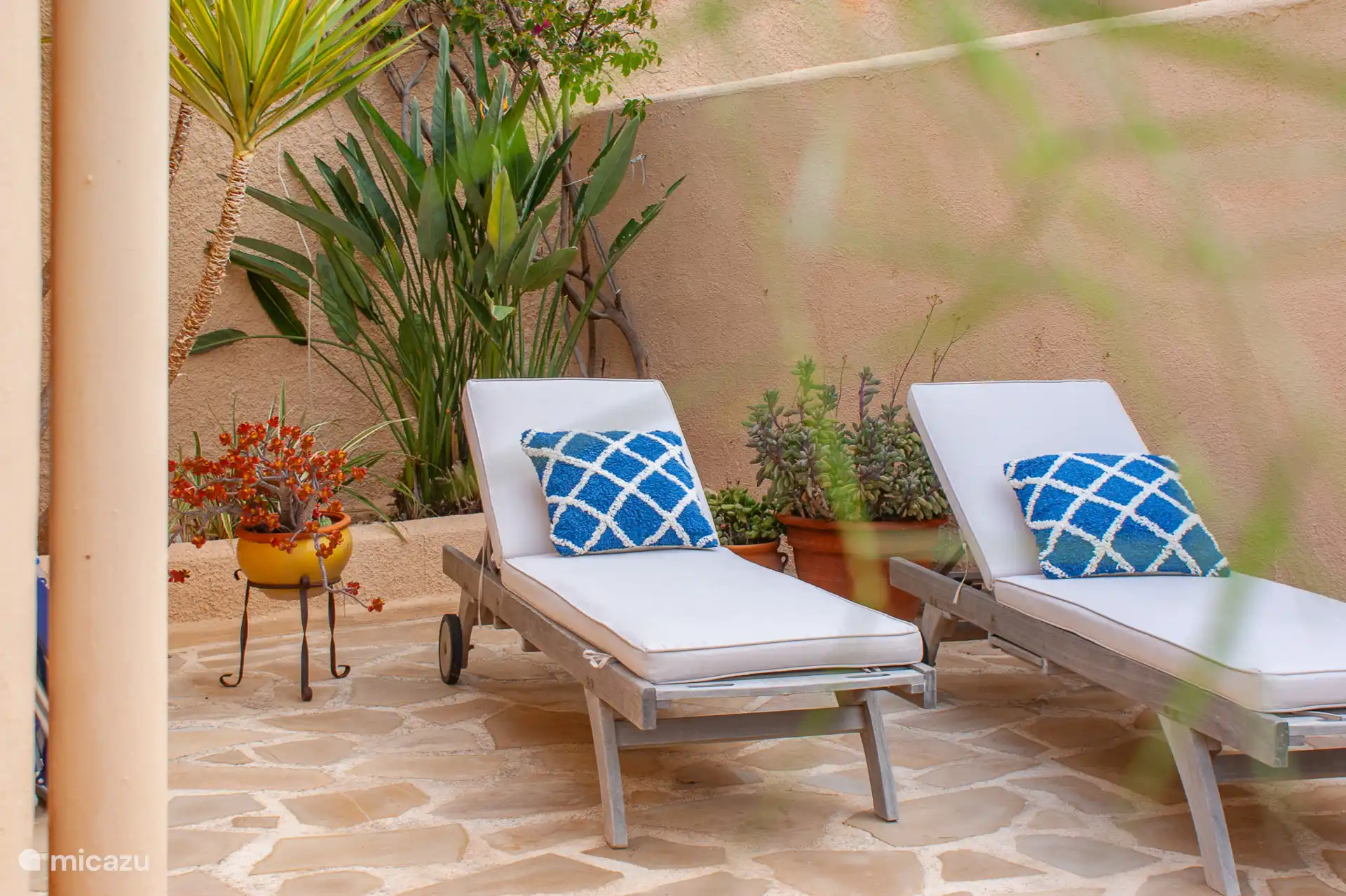 Tweede terras op de benedenverdieping met een zithoek, hangmat, buitendouche en twee zonnebedden.