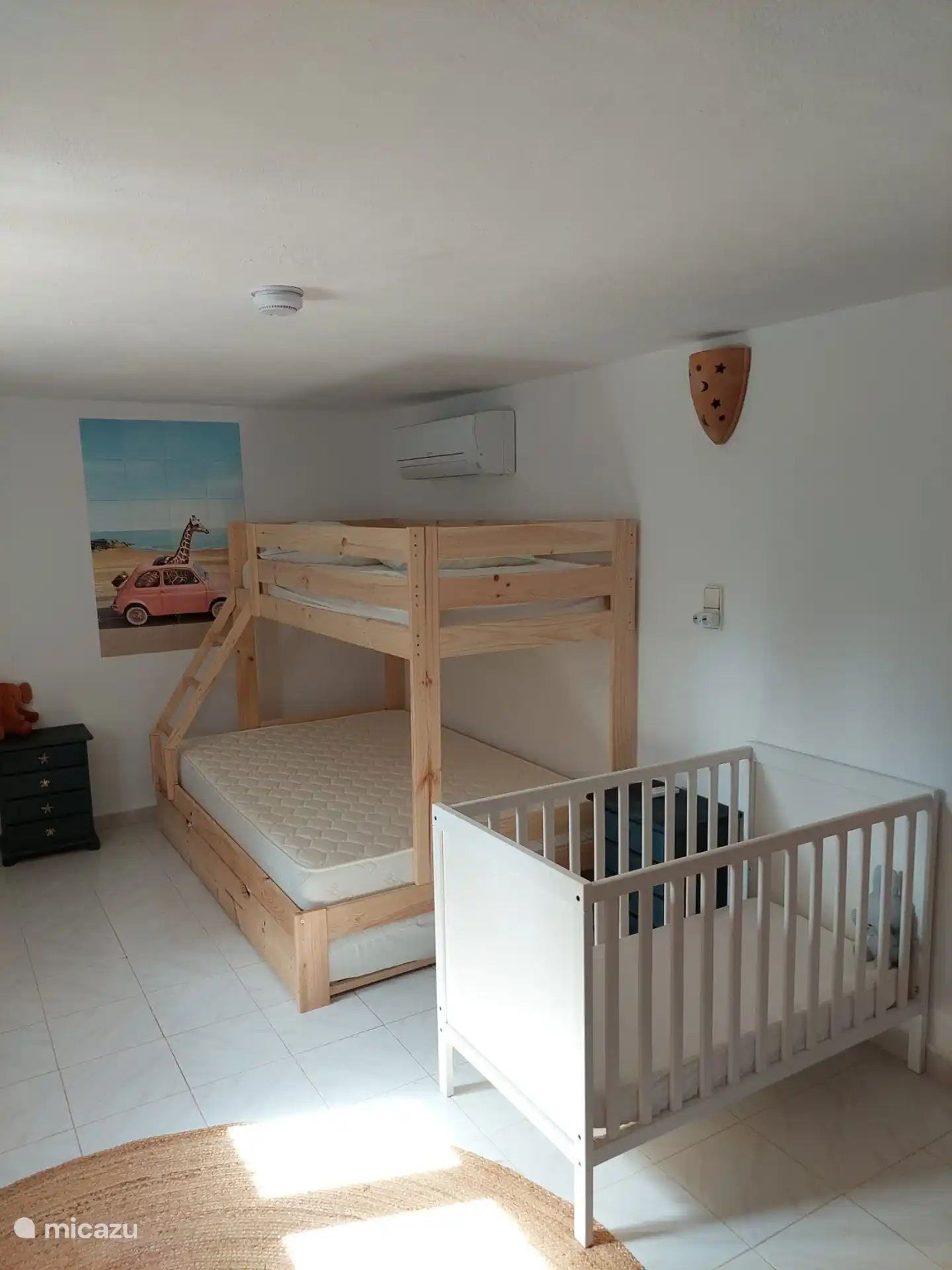 Slaapkamer met stapelbed, twijfelaar formaat voor het onderste bed, een uitschuifmatras en ledikant op de begane grond. 