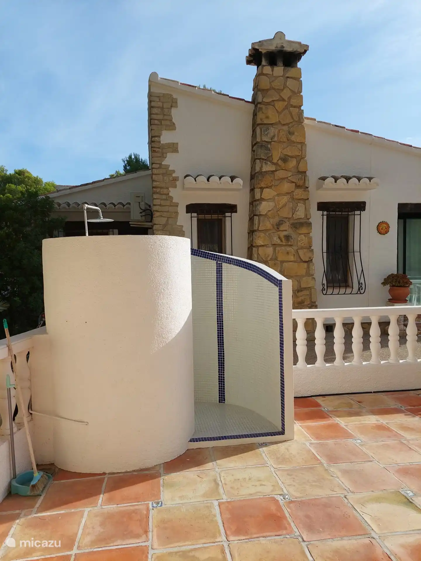 Buitendouche bij het zwembad en aanzicht naar het huis kijkend naar de 2 ramen van de woonkamer. 