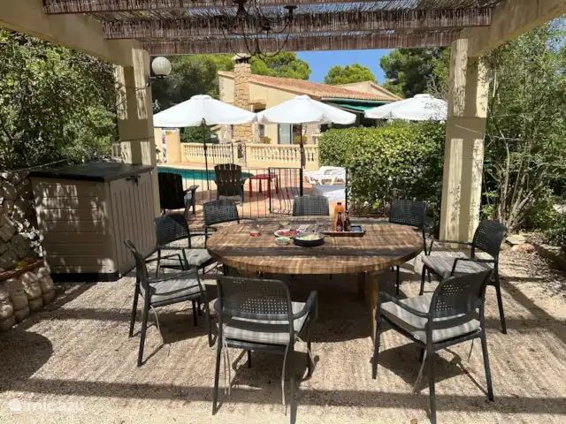 Siempre Verde - Con piscina climatizada en España, Costa Blanca, Moraira - villa Mesa redonda bajo la pérgola en semisombra con vista a la piscina y la casa detrás de ella.