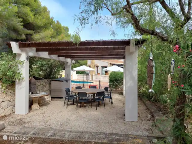 Siempre Verde - Con piscina climatizada en España, Costa Blanca, Moraira - villa Mesa redonda bajo la pérgola mirando hacia la casa.
