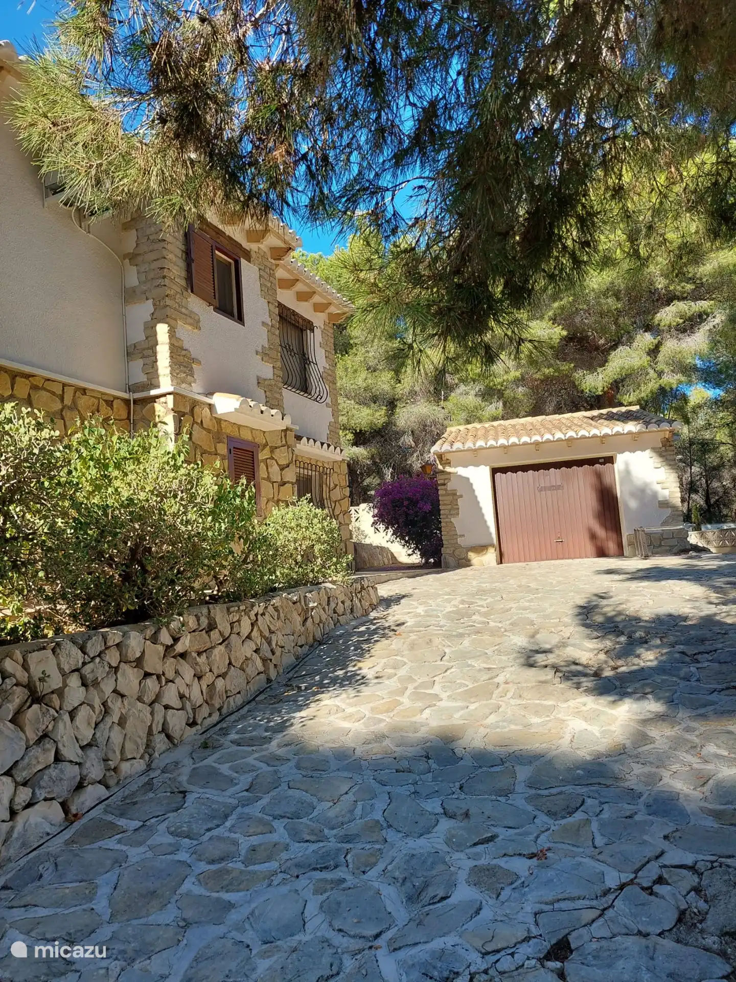 Zijkant van het huis met de schuur. 