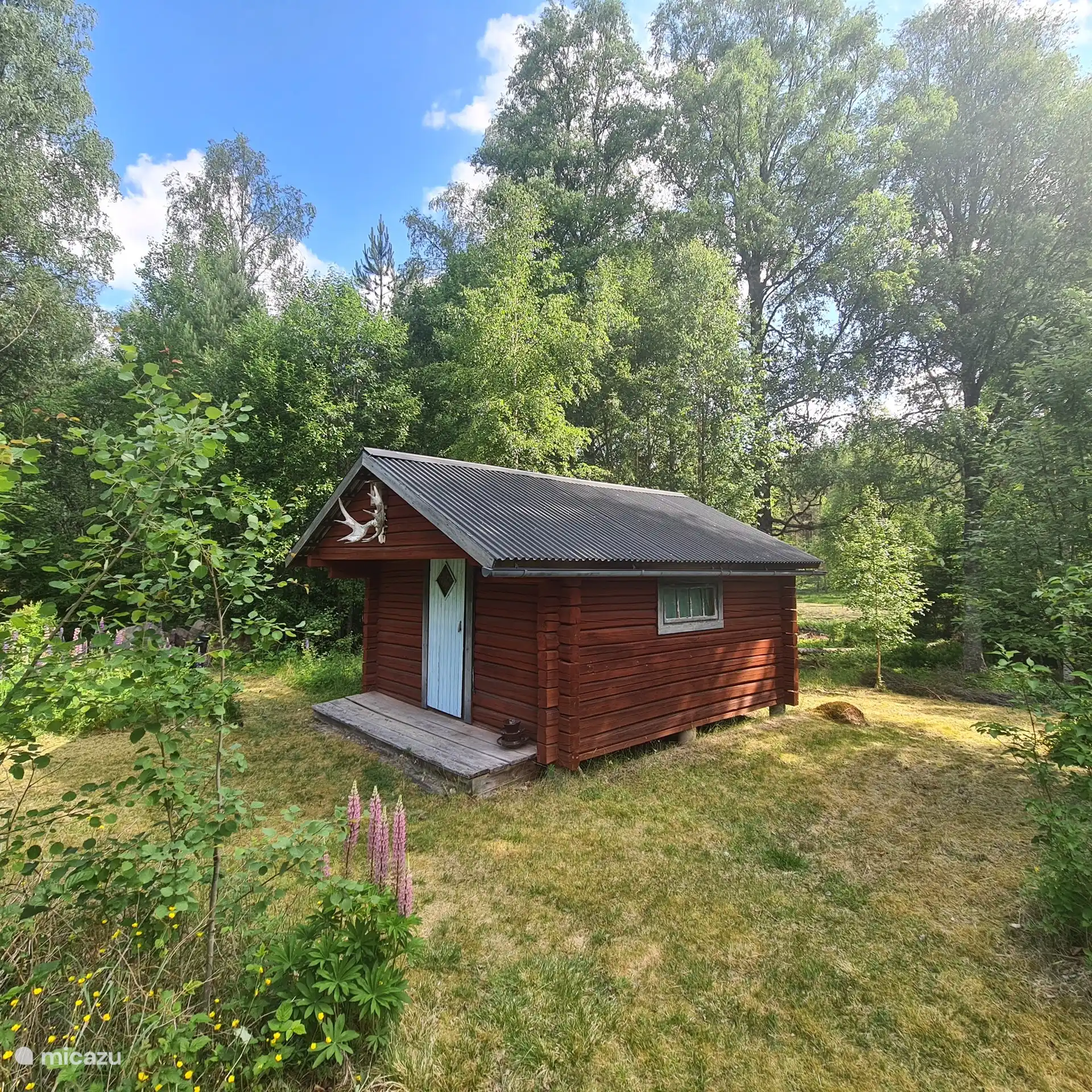 Schwedische Blockhütte im Garten mit mehreren einfachen Betten. 