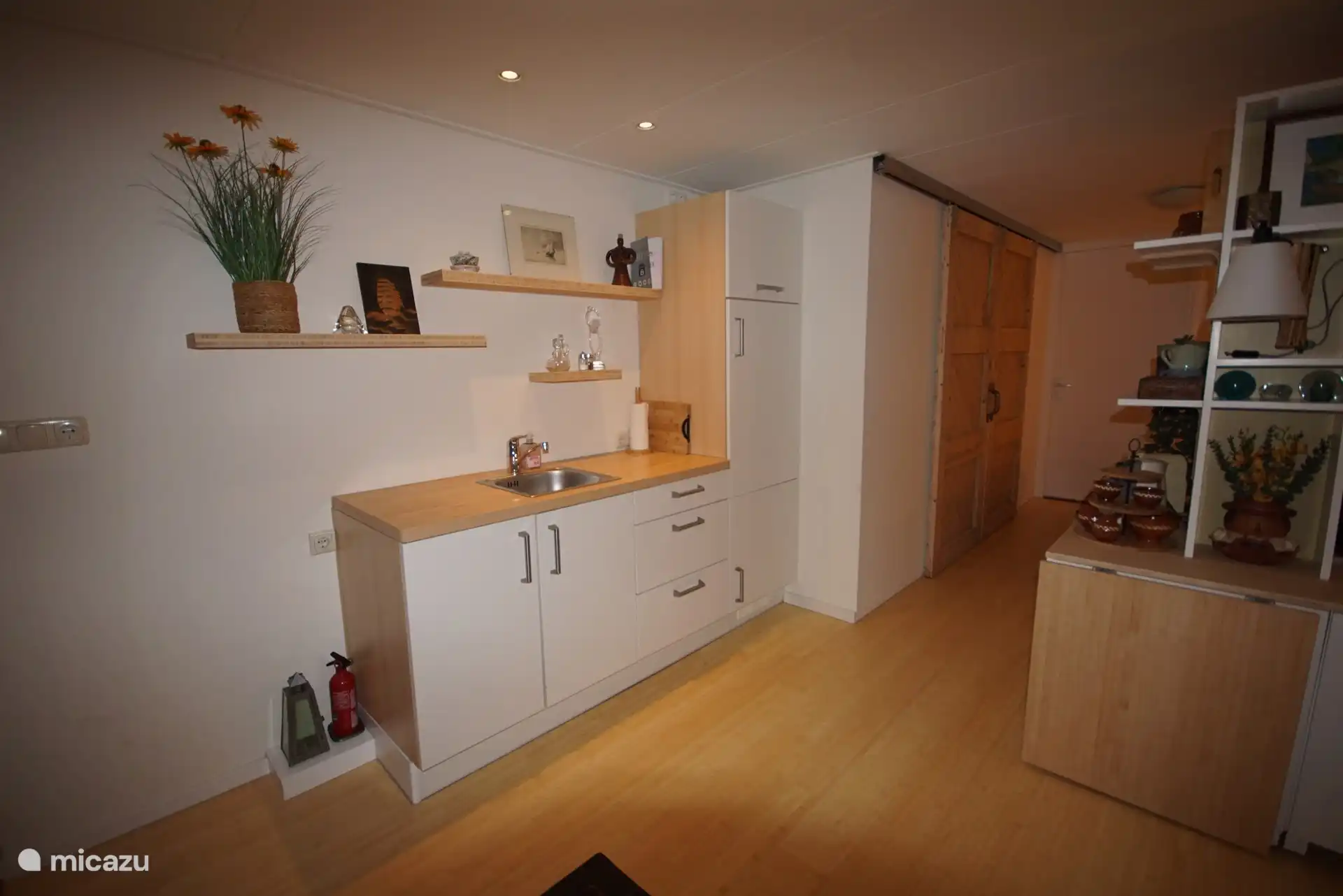 Via de doorgang kom je in het slaapgedeelte. Daar zie je links de badkamer met de gesloten schuifdeuren.