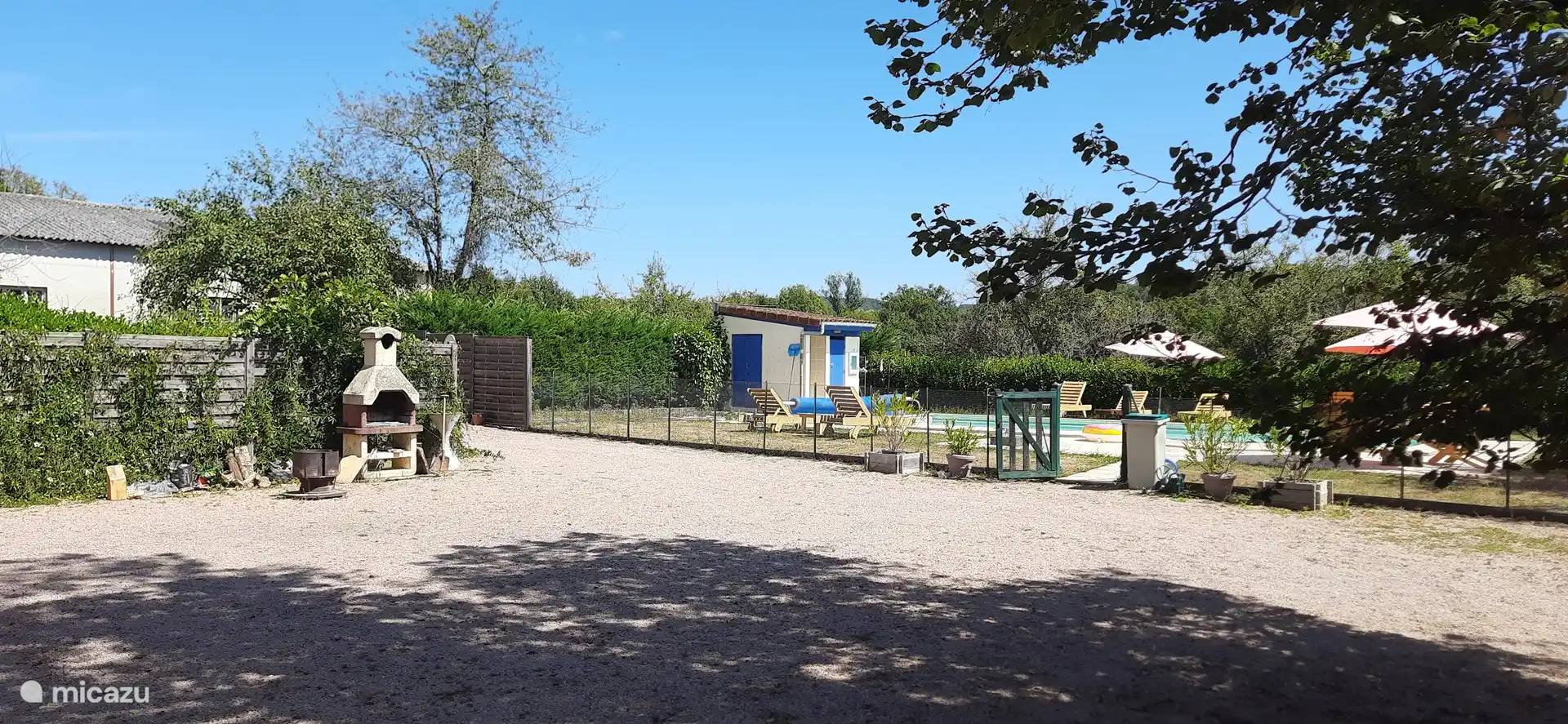 Vista a la piscina y barbacoa desde la terraza cubierta.