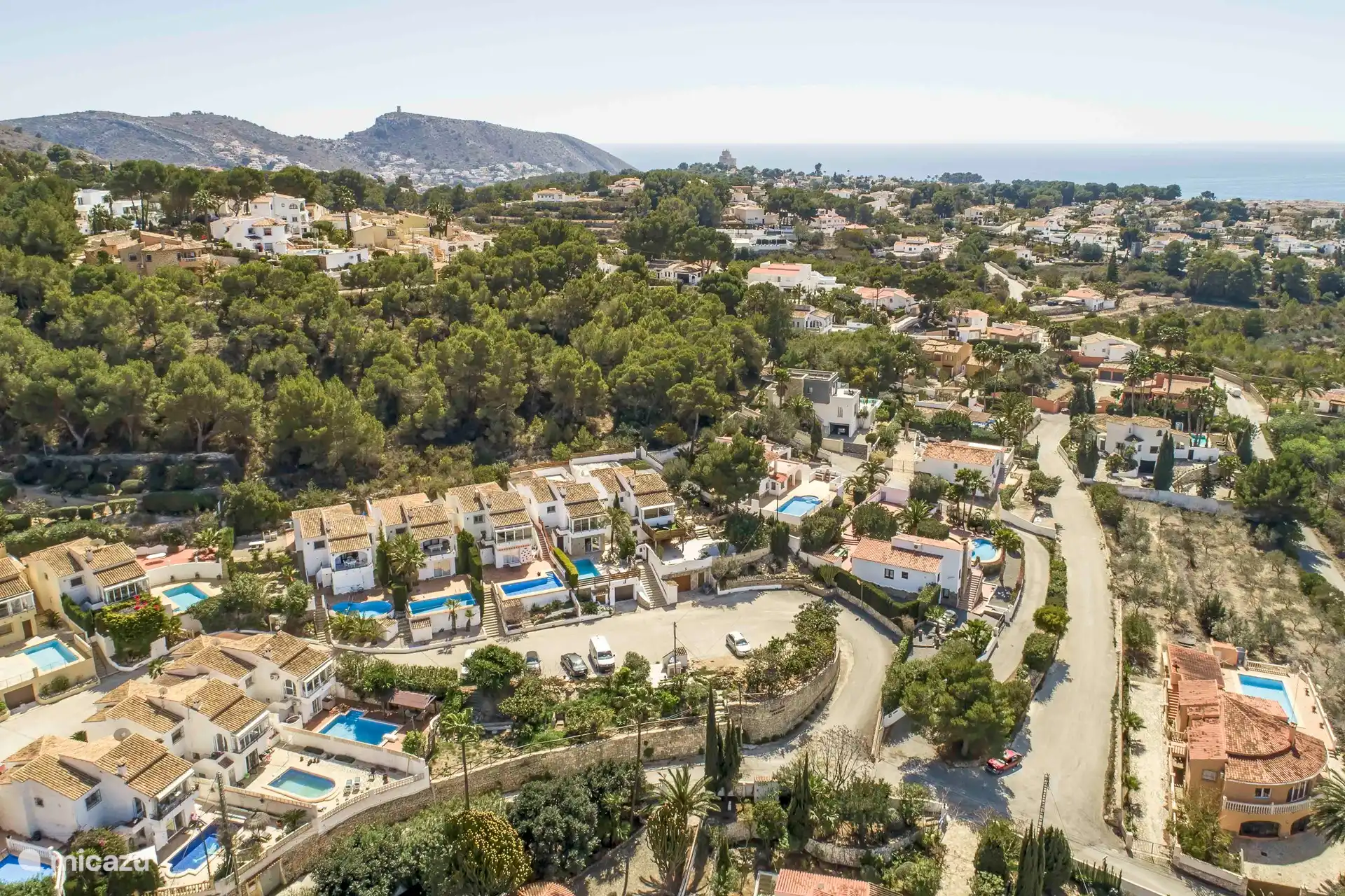 Ci-dessus photo de la maison. Derrière la maison il y a une petite forêt et plus loin on aperçoit la mer. 
