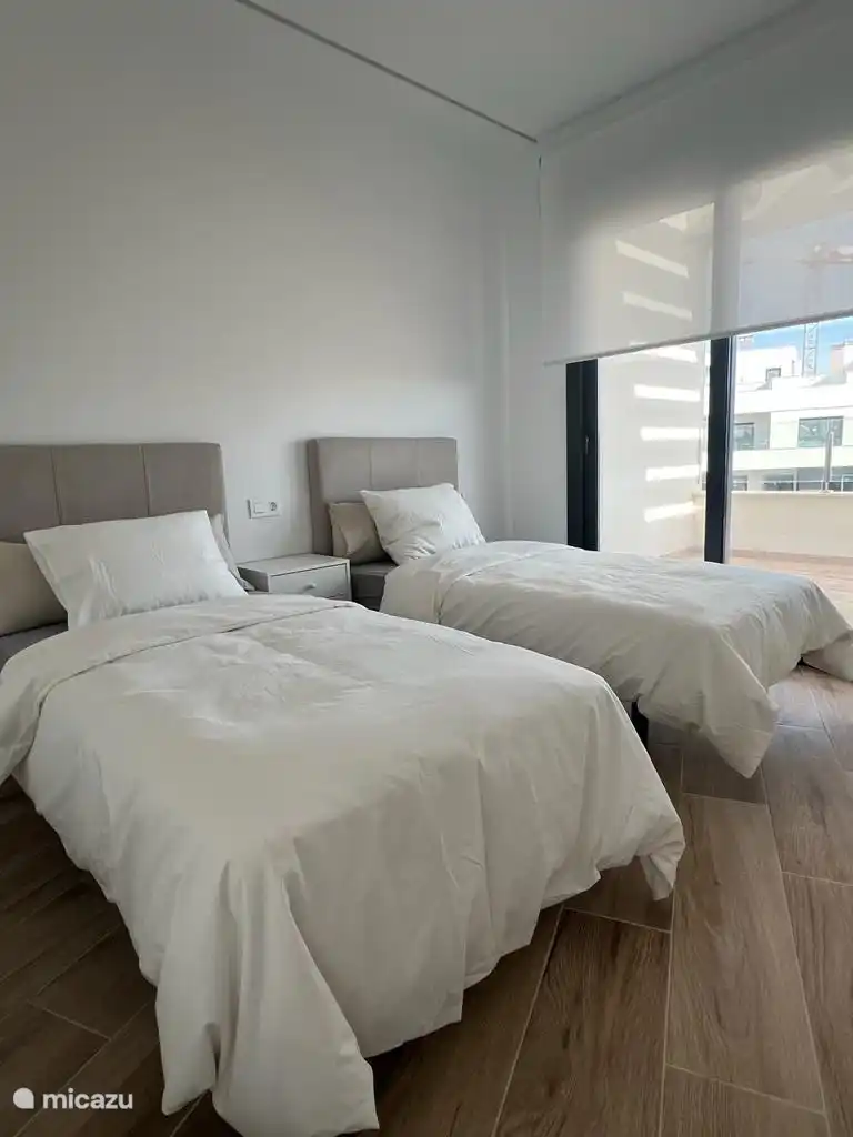 Dormitorio adicional con 2 camas individuales que también está adyacente al balcón que da a la piscina