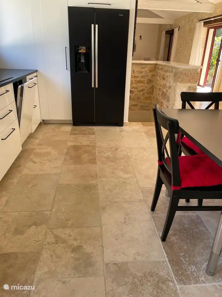 Küche mit amerikanischem Kühlschrank mit Eismaschine und daneben die Natursteintreppe zum Keller.