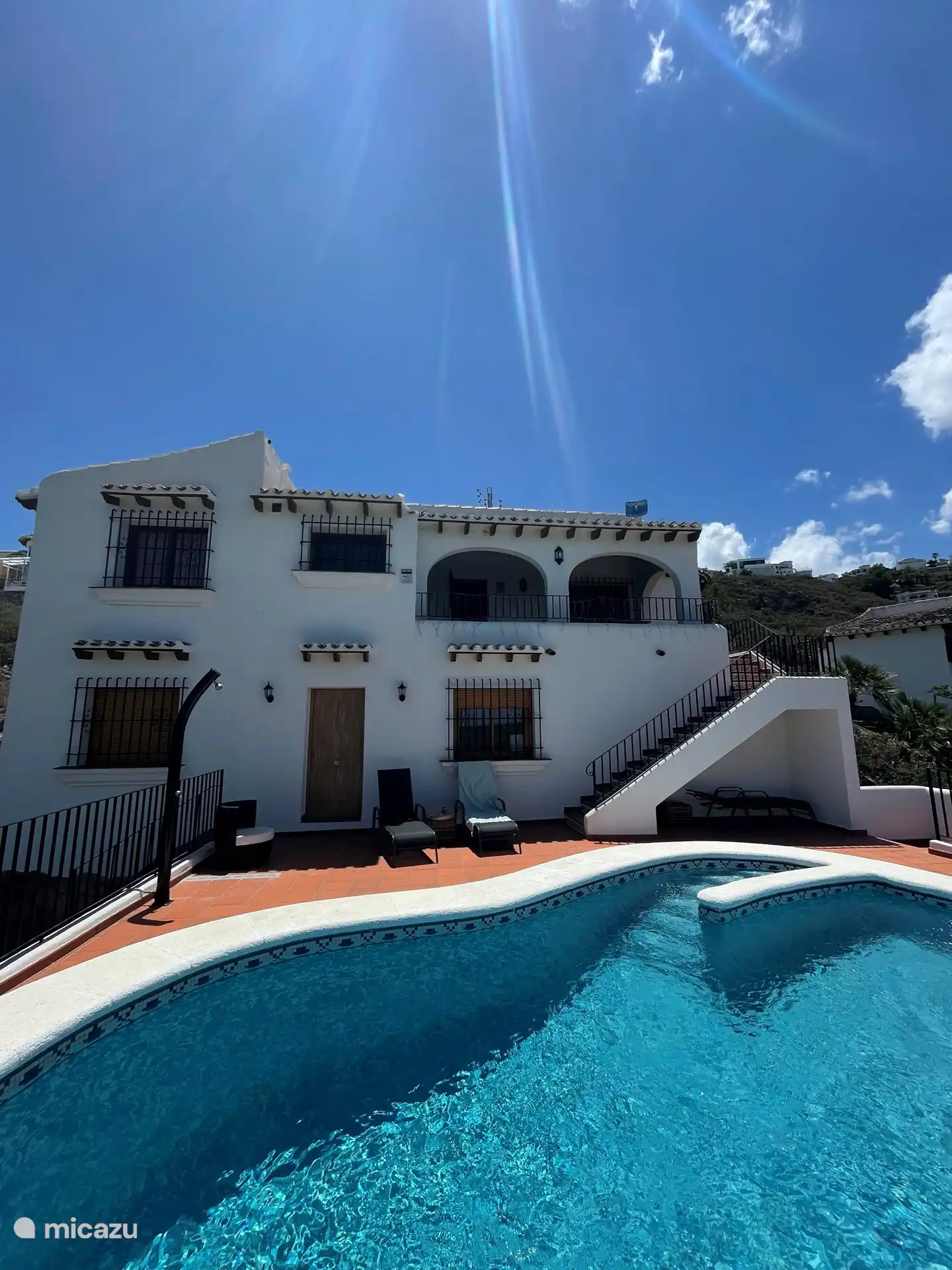Douche extérieure et transats autour de la piscine