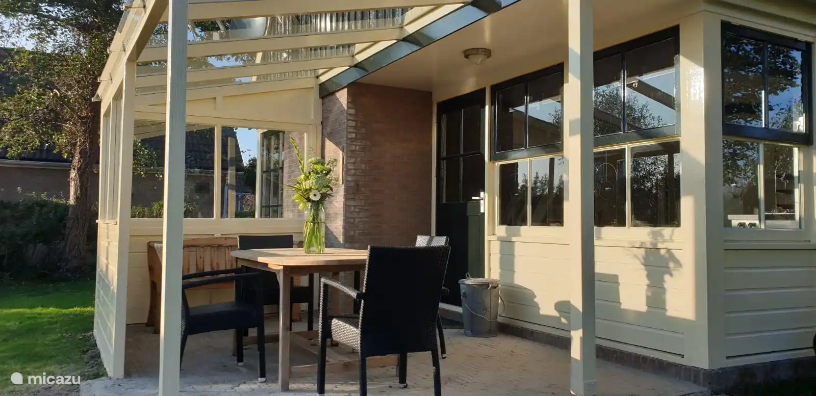 Onder de zonnige overkapping met glazen dak geniet je van het vroege voorjaar tot het late najaar van het buitenleven.