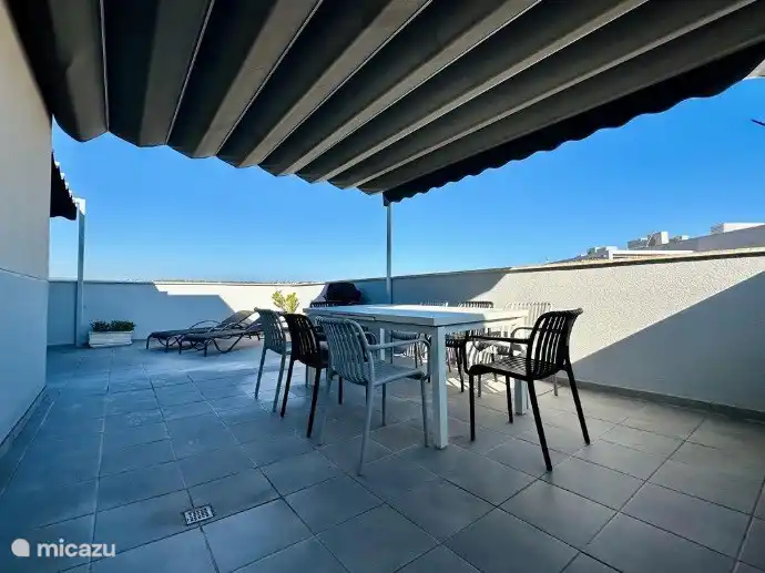 Terrasse sur le toit avec table à manger spacieuse. 