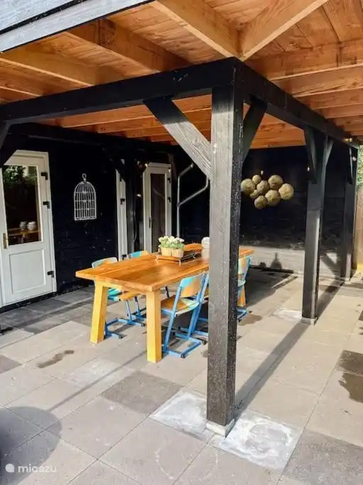 großer Esstisch draußen unter Dach