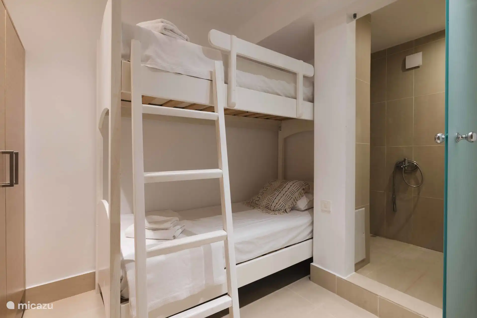 Chambre d’amis avec un lit superposé et salle de bain attenante avec douche