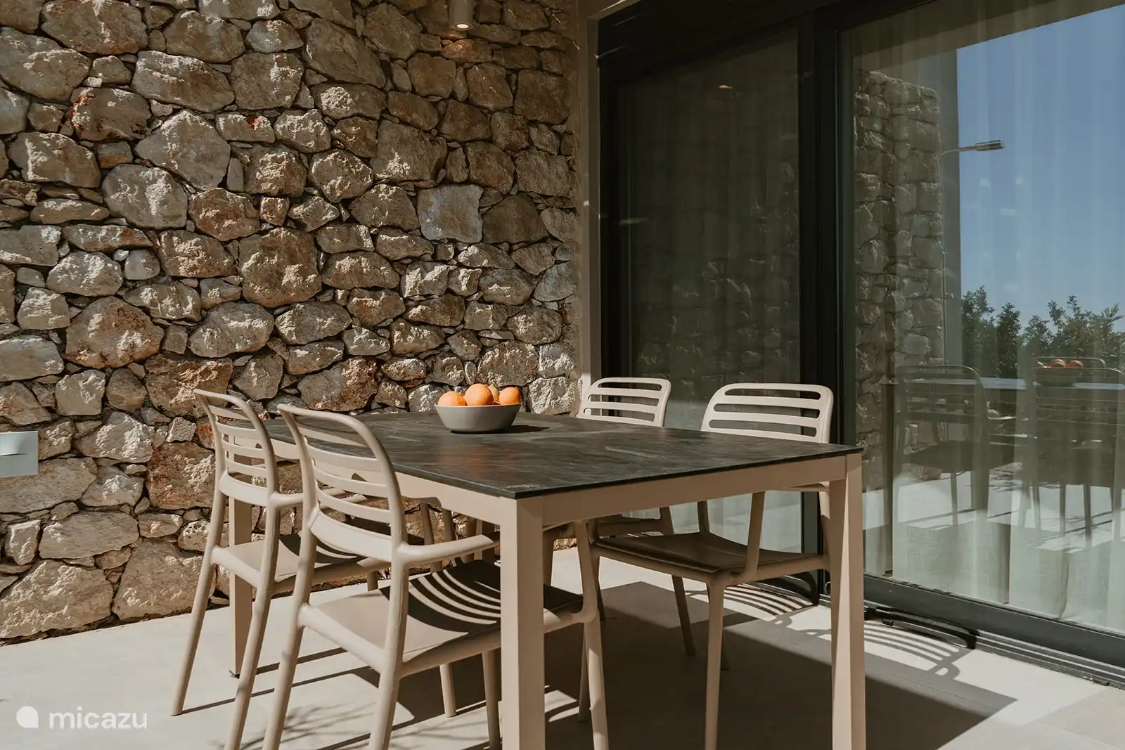 Der Esstisch draußen auf der Terrasse. Neben dem Esstisch befindet sich auch die Außendusche.