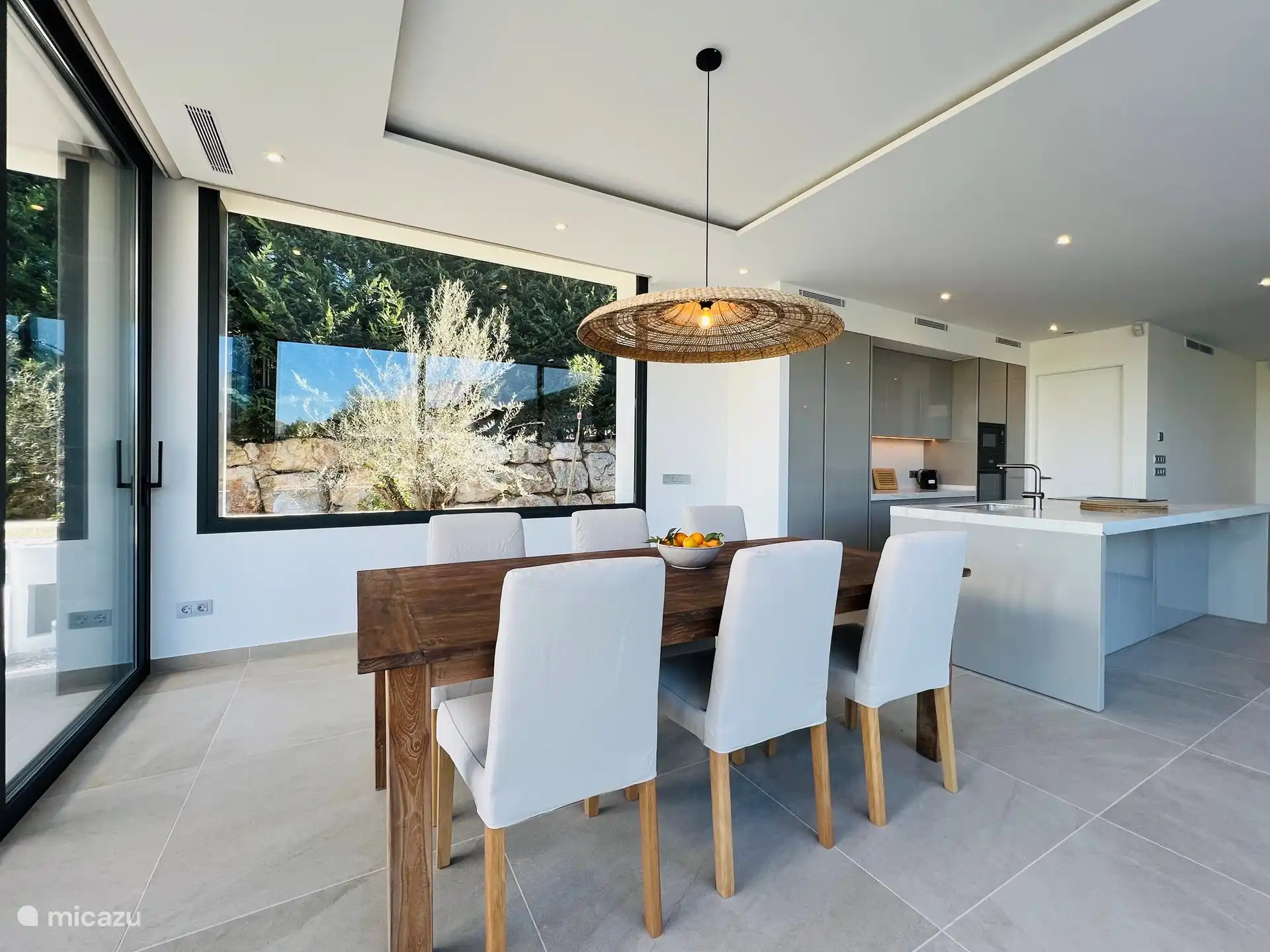 Esszimmer mit offener Küche und Blick auf den Pool.