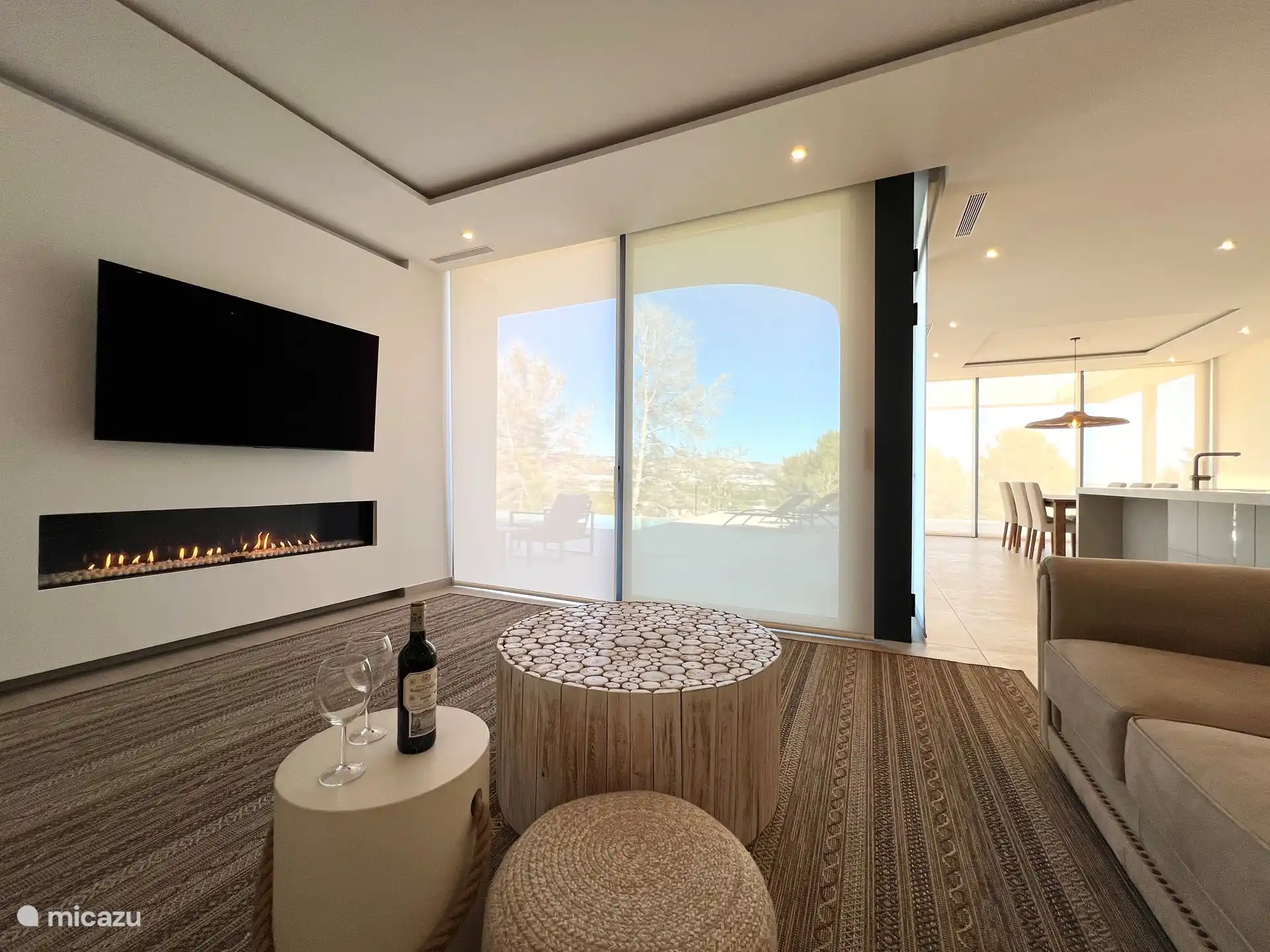 Wohnzimmer mit Gaskamin und Blick auf den Pool und die Terrasse.