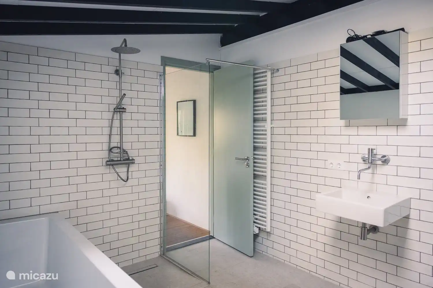 Geräumiges Badezimmer mit großer Badewanne und Regendusche