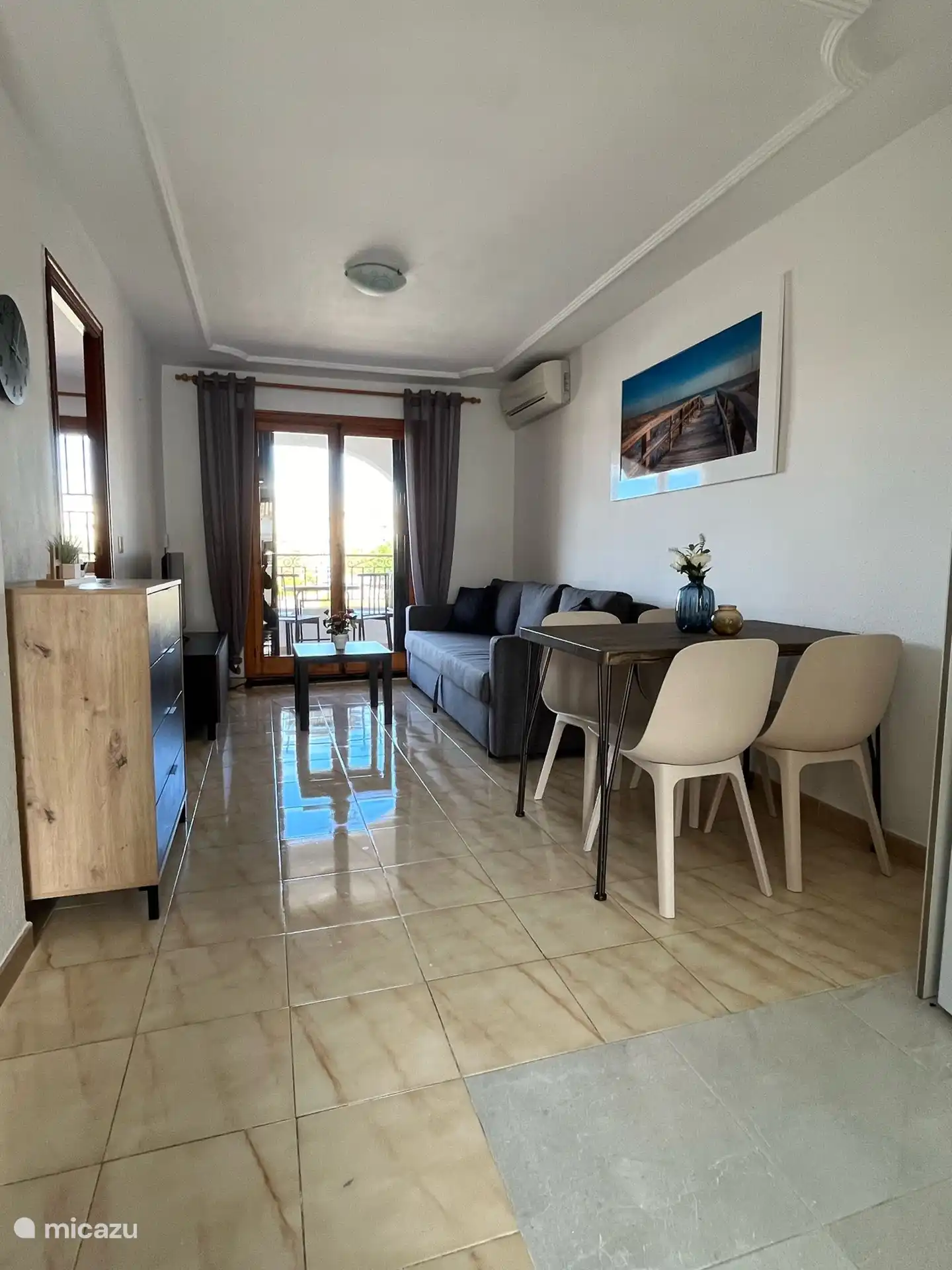 Das Wohnzimmer mit bequemer Doppelschlafcouch. Klimaanlage und Zugang zum Balkon.