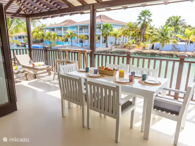 villa huren in Bonaire, Bonaire, Kralendijk – Blou Bonaire Waterlands Village De veranda biedt een prachtig uitzicht over het water. Hier kan je aan een ruime eettafel lekker eten. Ook staan er twee ligbedden en is er een zithoek aanwezig. Een heerlijke plaats om te vertoeven wanneer je je op het resort bevindt.