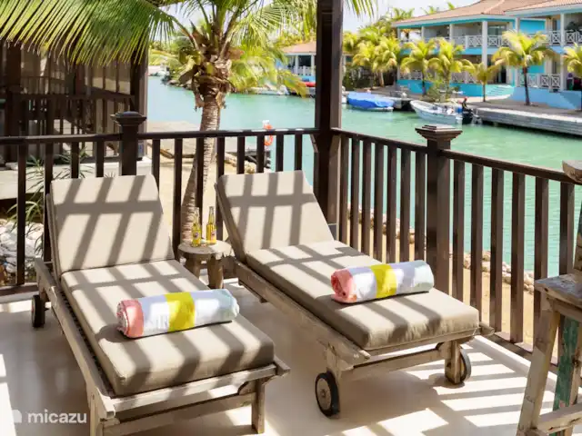 villa huren in Bonaire, Bonaire, Kralendijk – Blou Bonaire Waterlands Village De veranda biedt een prachtig uitzicht over het water. Hier kan je aan een ruime eettafel lekker eten. Ook staan er twee ligbedden en is er een zithoek aanwezig. Een heerlijke plaats om te vertoeven wanneer je je op het resort bevindt.