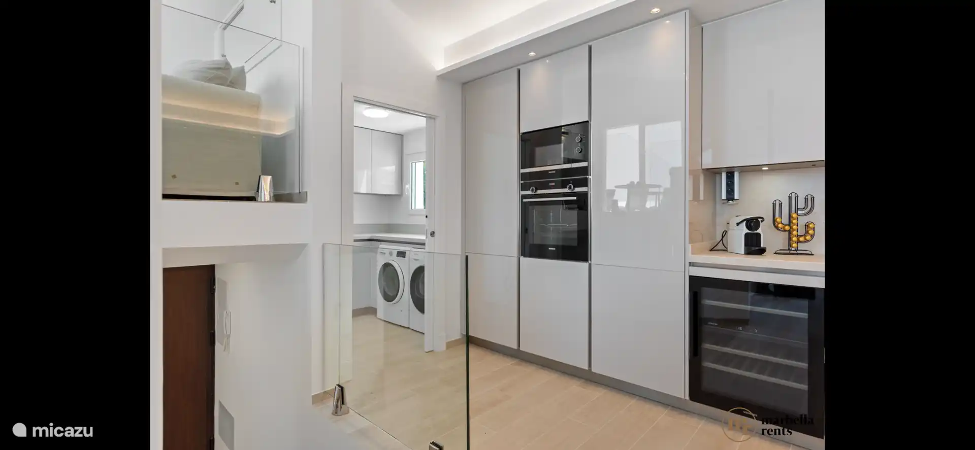 Küche mit Backofen, Mikrowelle und Weinkühler sowie Hauswirtschaftsraum mit Waschmaschine und Trockner