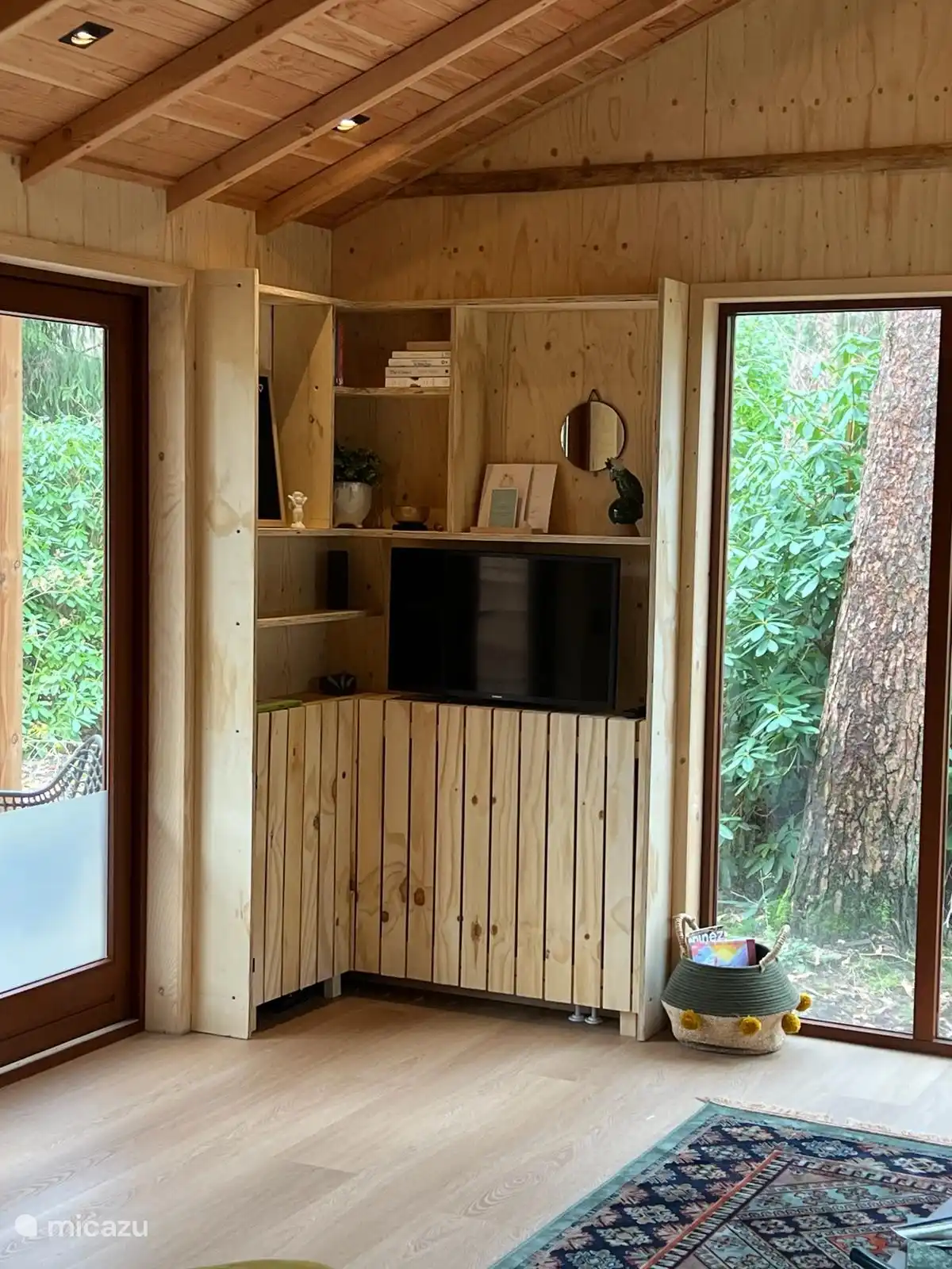 Selbstgebauter Holzschrank mit Sachen, Büchern und dem Fernseher auf einer beweglichen Wandhalterung