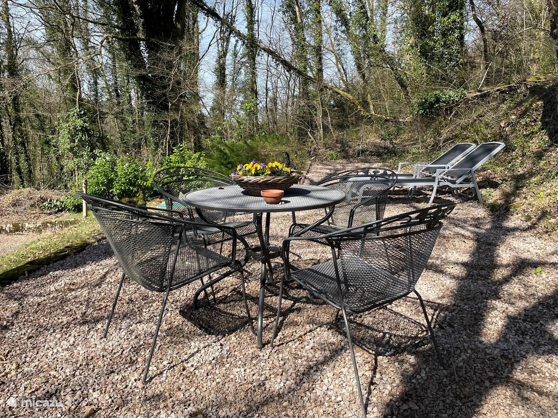 Gartenmöbel unter den Bäumen mit 2 Sonnenliegen dahinter