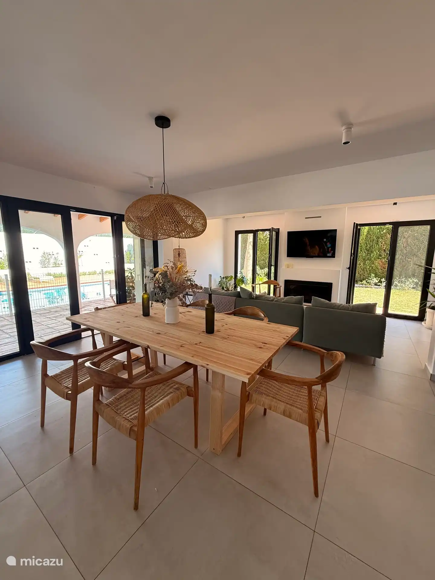 Großer Essbereich neben offener Küche, Wohnzimmer und Eingangsterrasse mit Blick auf den Garten und den Pool.  