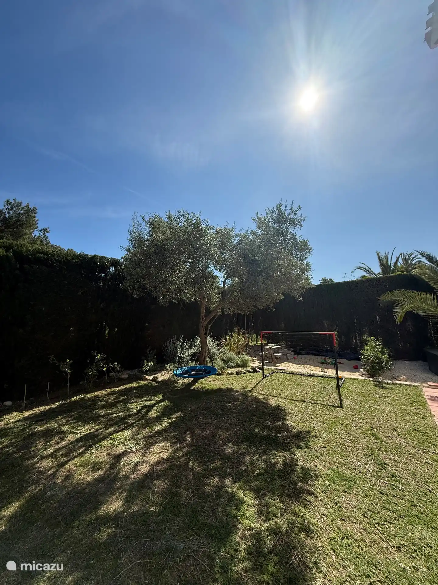 Garten mit Rasen- und Sandfläche für Kinder.