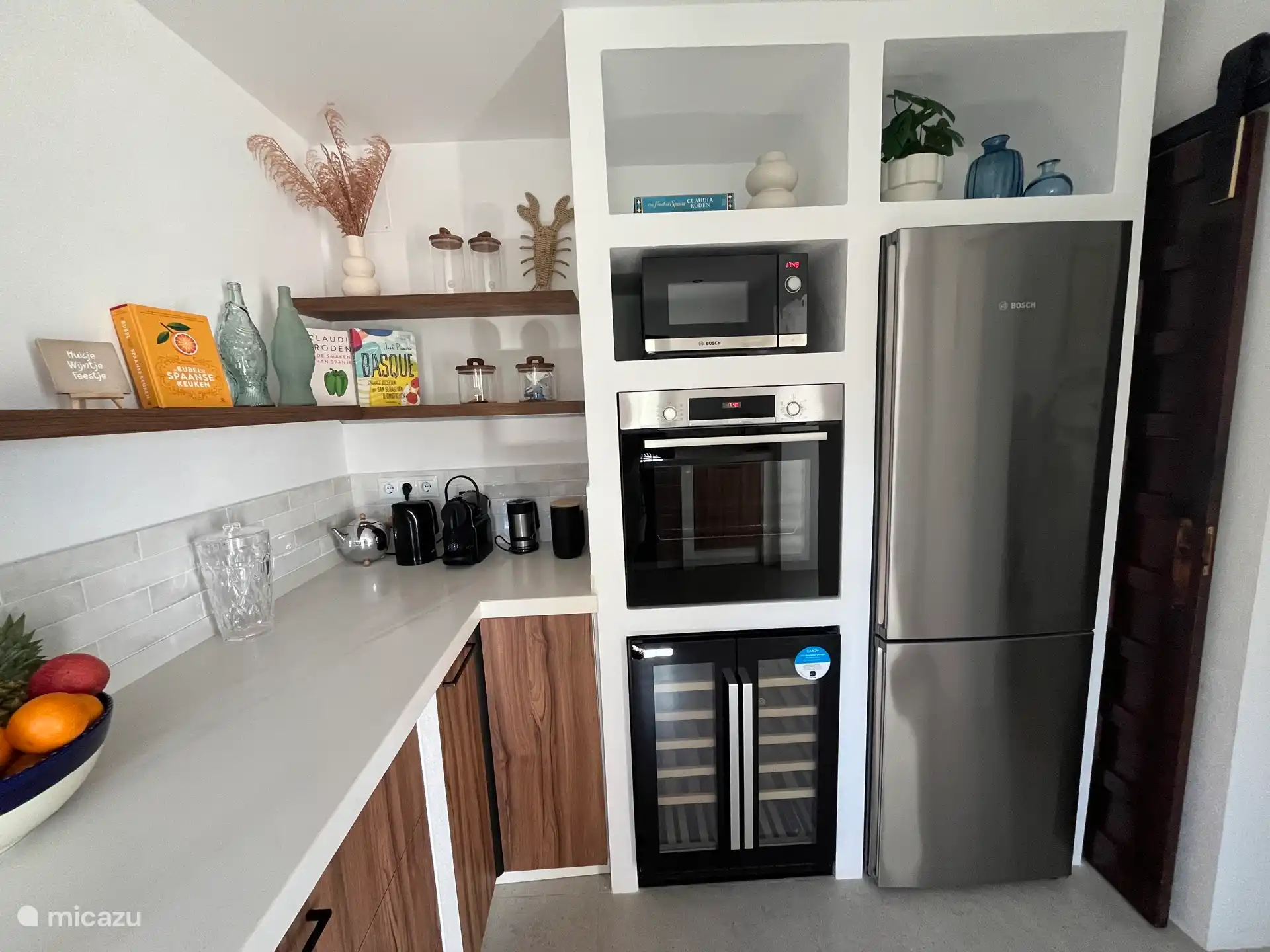 Keuken voorzien van magnetron, oven, wijnklimaat kast en inductie kookplaat en vaatwasser.