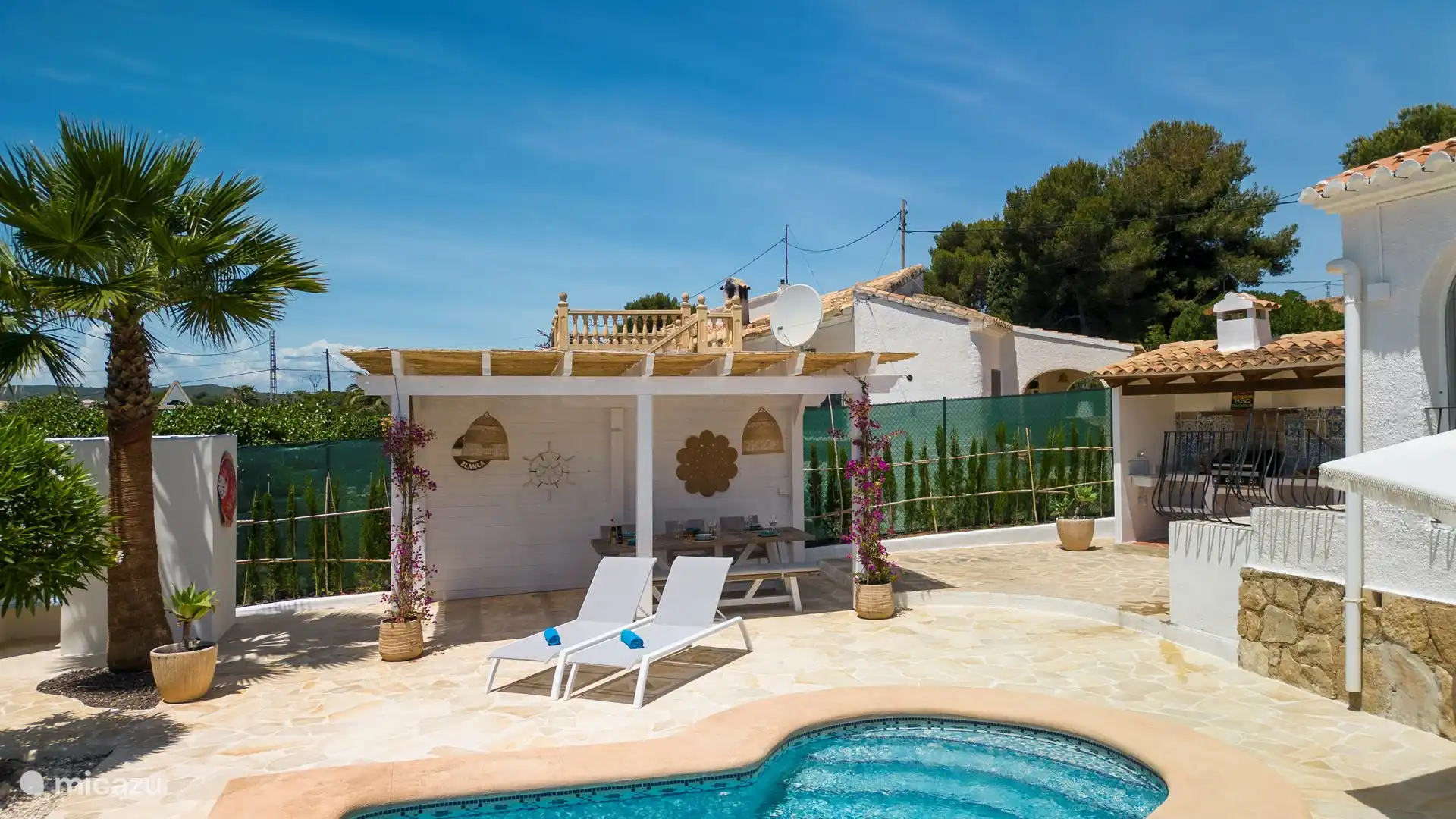 Geräumige Terrasse mit überdachter Pergola und Außenküche.