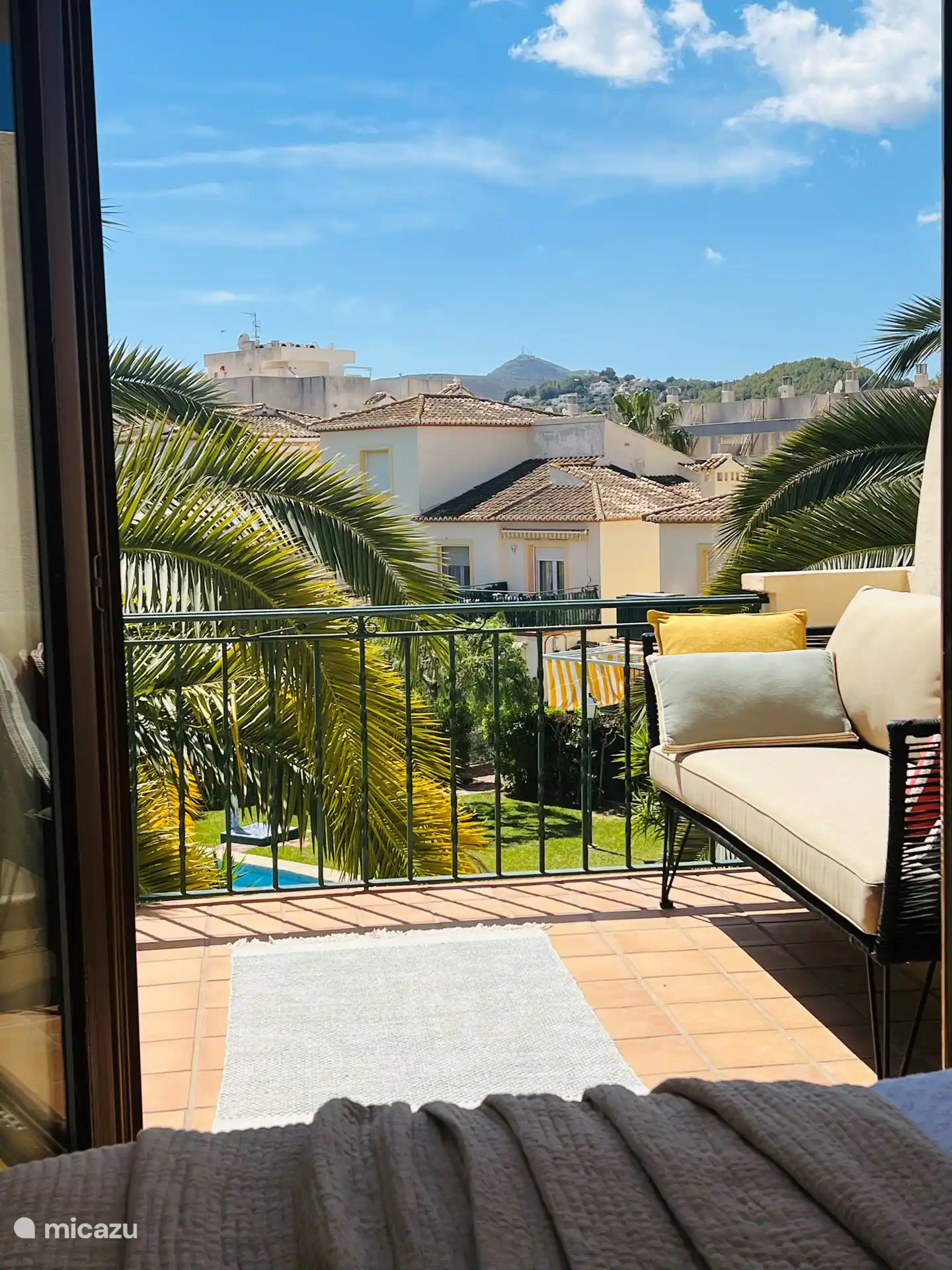 Relájese en la terraza orientada al sur con una gran vista del hermoso jardín comunitario más grande y verde con la piscina más grande de Jávea.