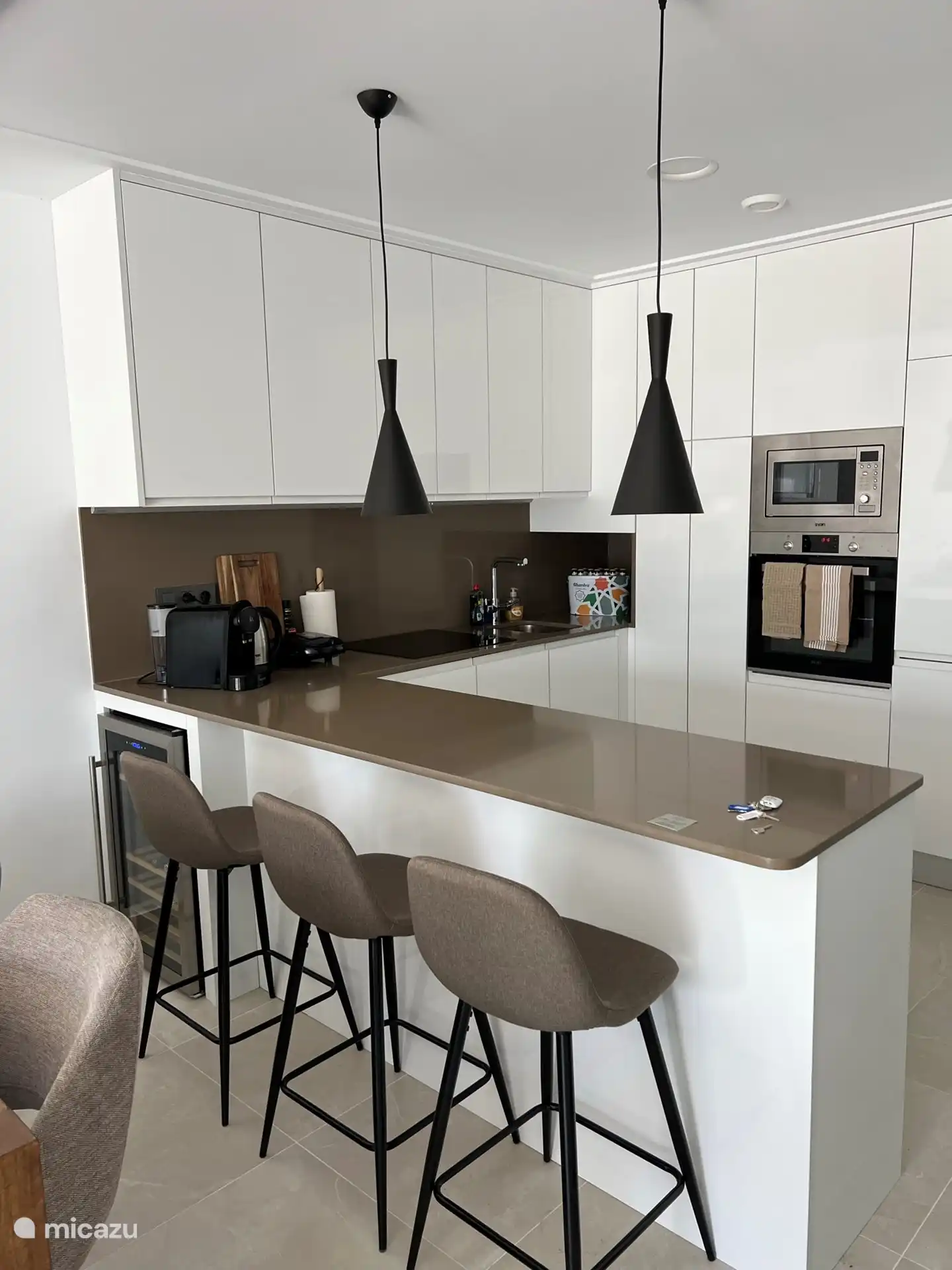 Küche mit Weinkühlschrank und Sitzgelegenheiten an der Theke