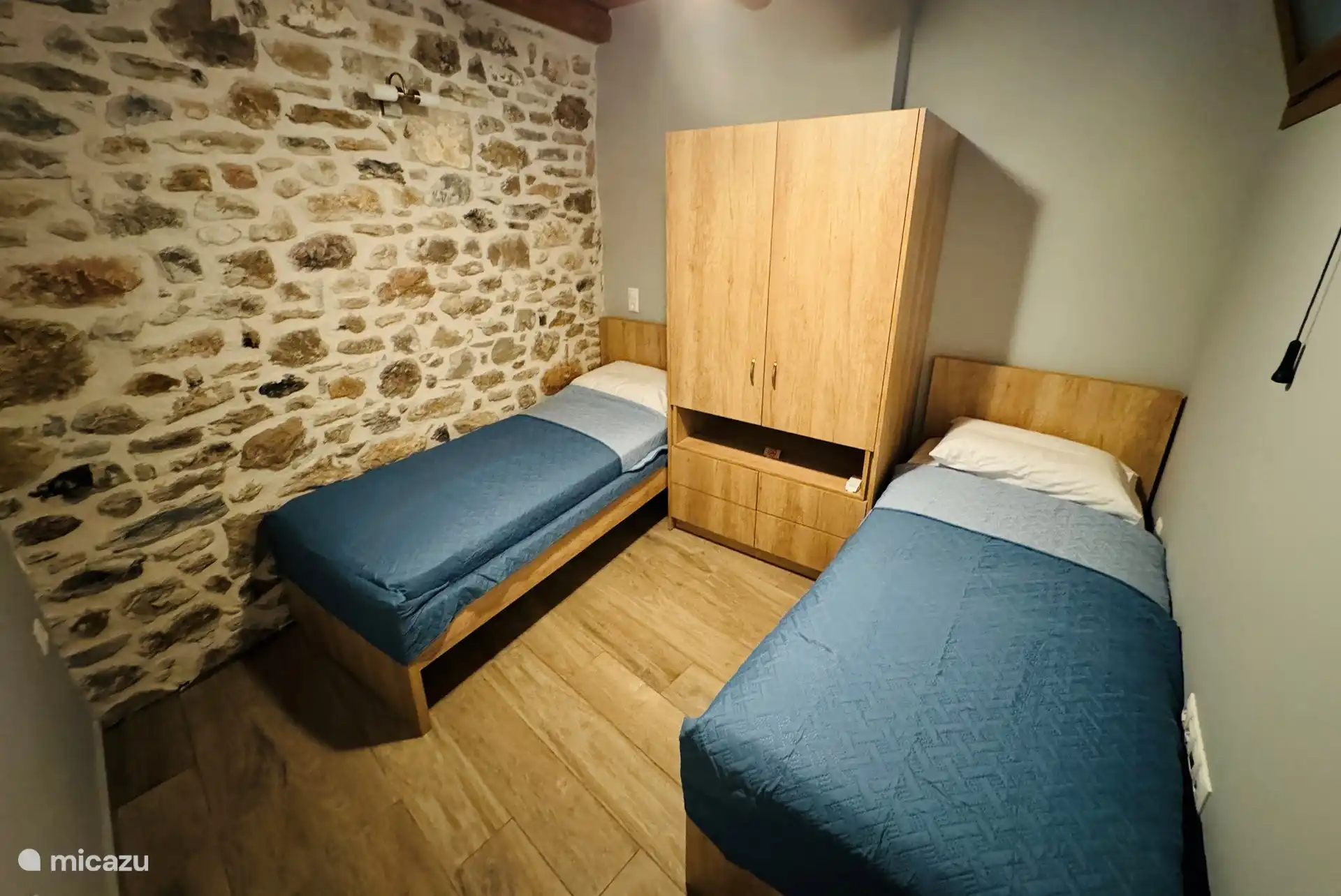 Schlafzimmer im Erdgeschoss mit zwei Einzelbetten und Deckenventilator.